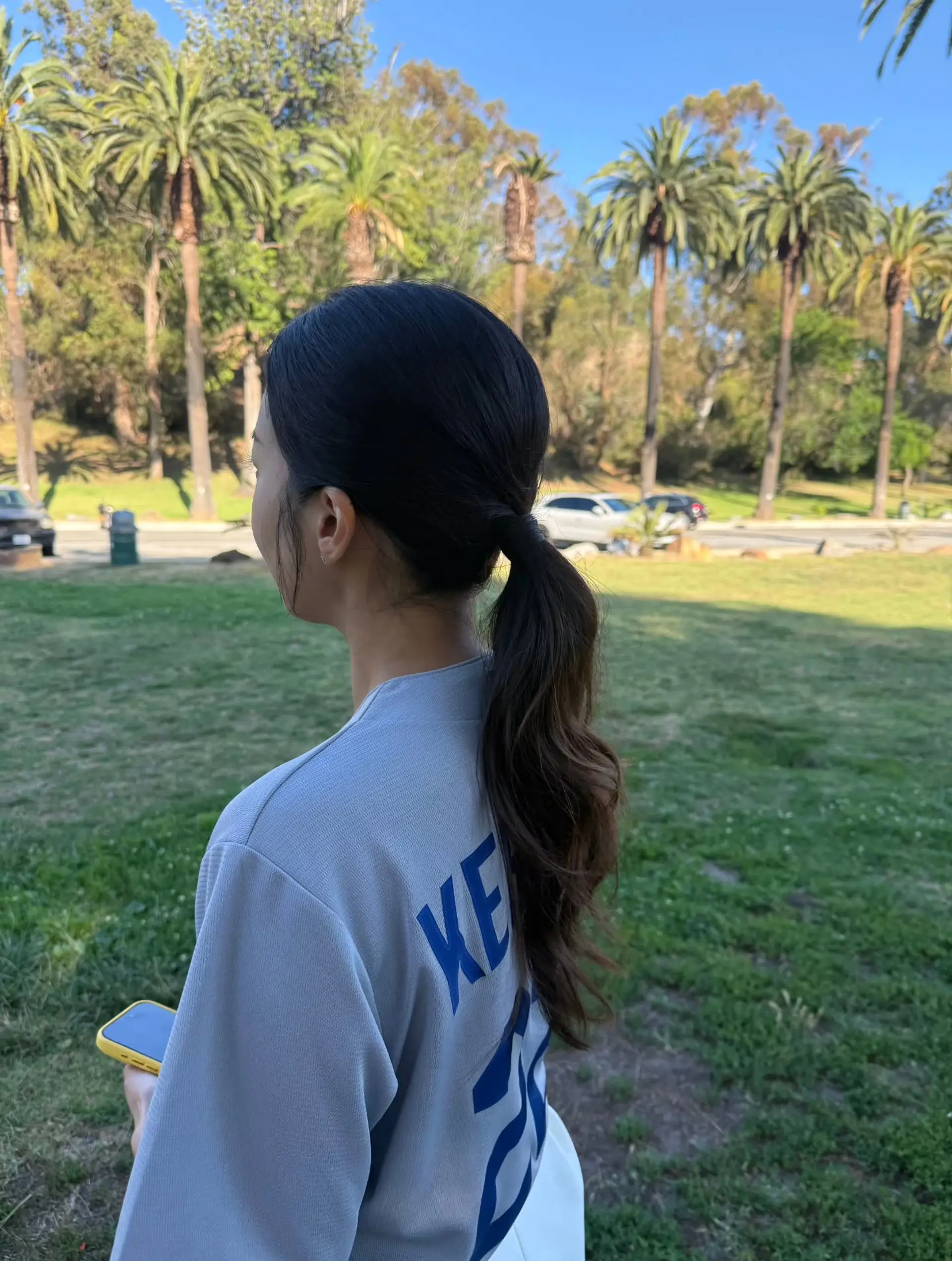 A sleek low ponytail gathered at the nape with loose, textured waves cascading down. 1