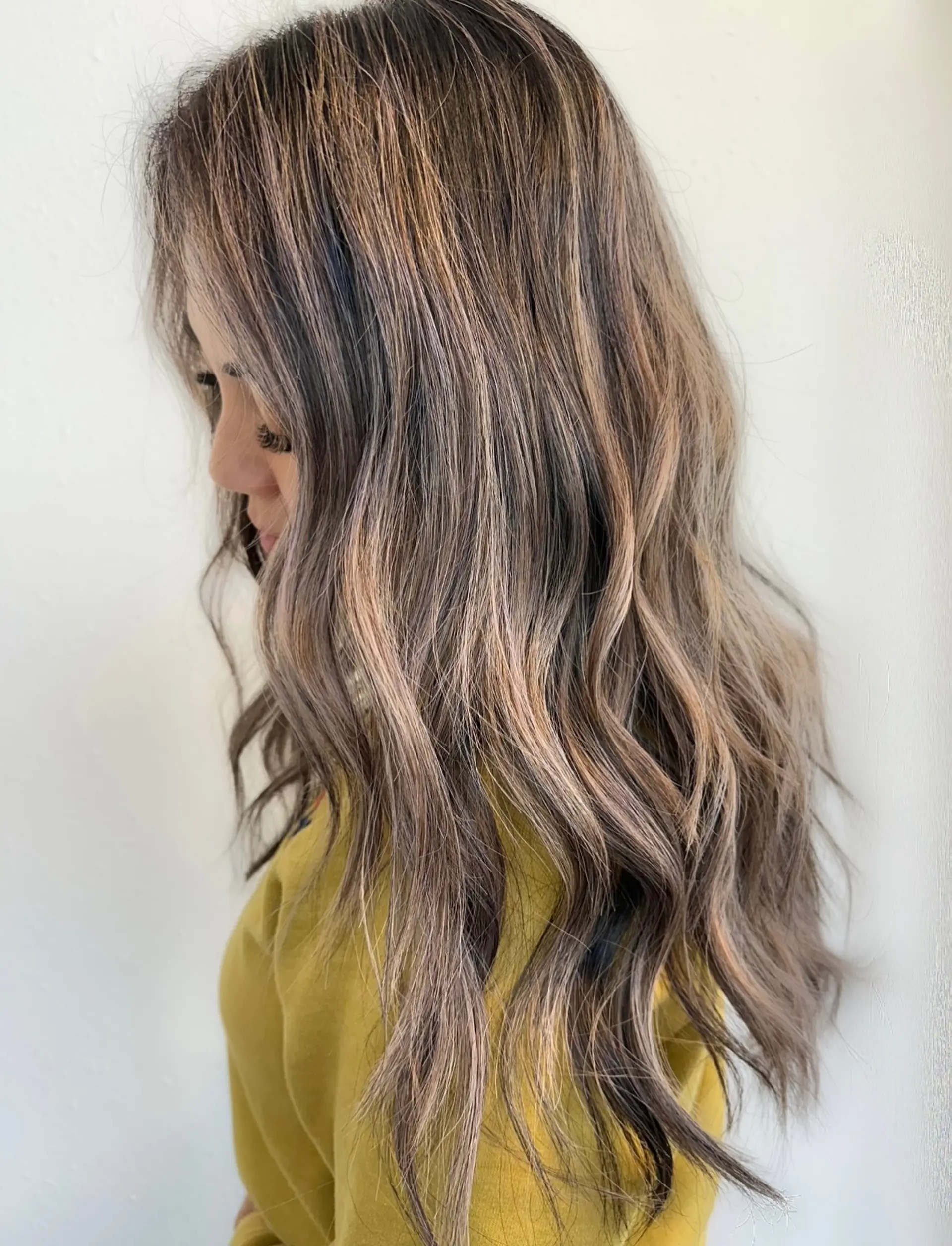 Long ash bronde hair featuring finely woven highlights and seamless balayage dimension, styled with relaxed, textured waves. 1