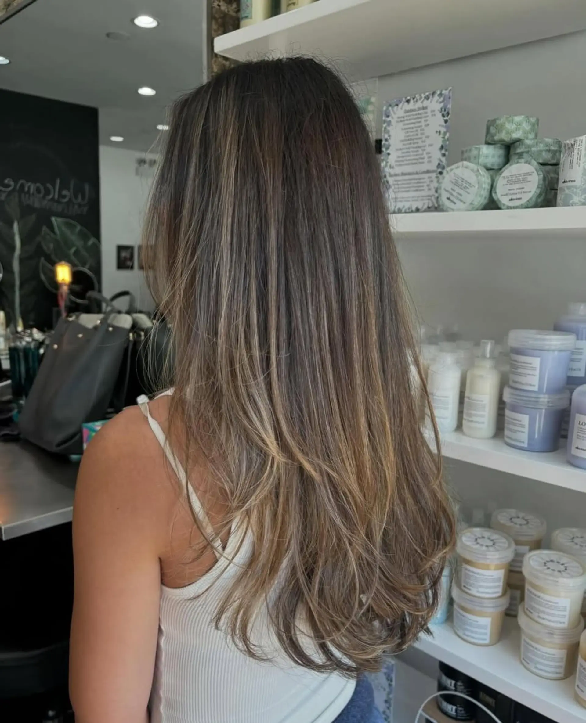 A stunning long, layered hairstyle featuring bronde balayage with seamless face-framing layers and soft, voluminous waves for a chic, dimensional look. 1