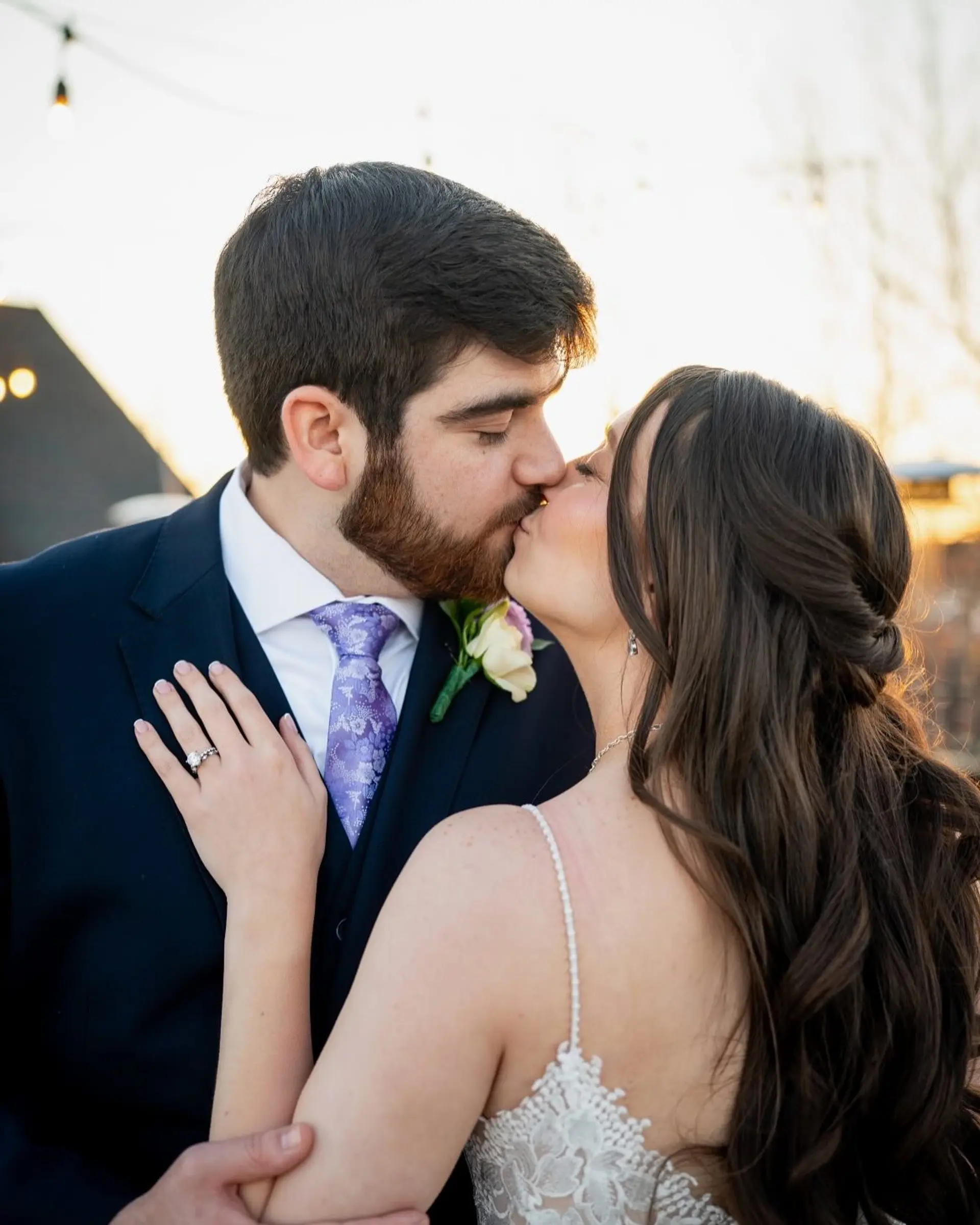 A romantic bridal half-up style with soft, cascading waves and twisted side sections, accompanied by clean and textured groom styling. 1