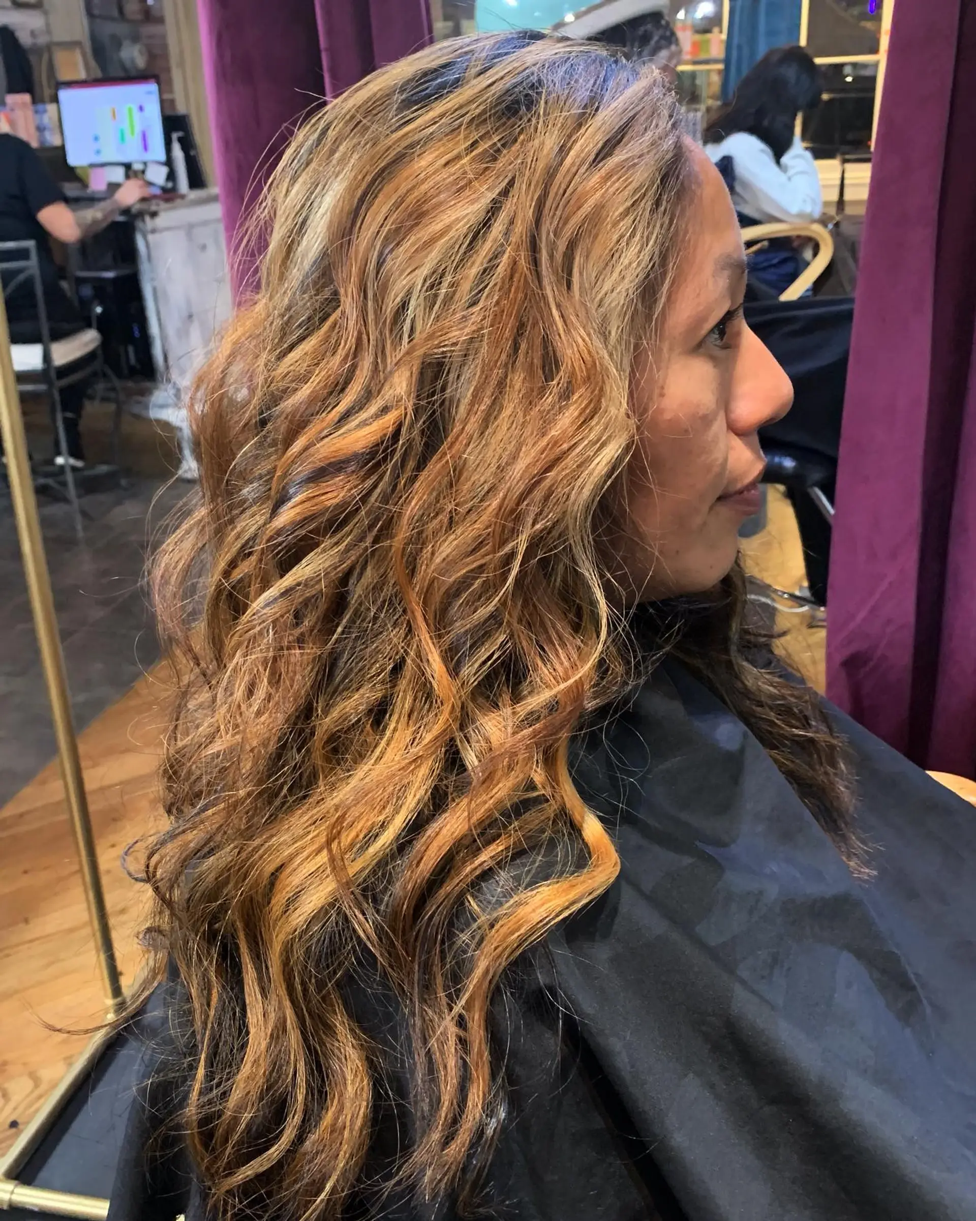 Long hair featuring warm caramel and golden blonde balayage highlights styled in textured, loose waves. 1