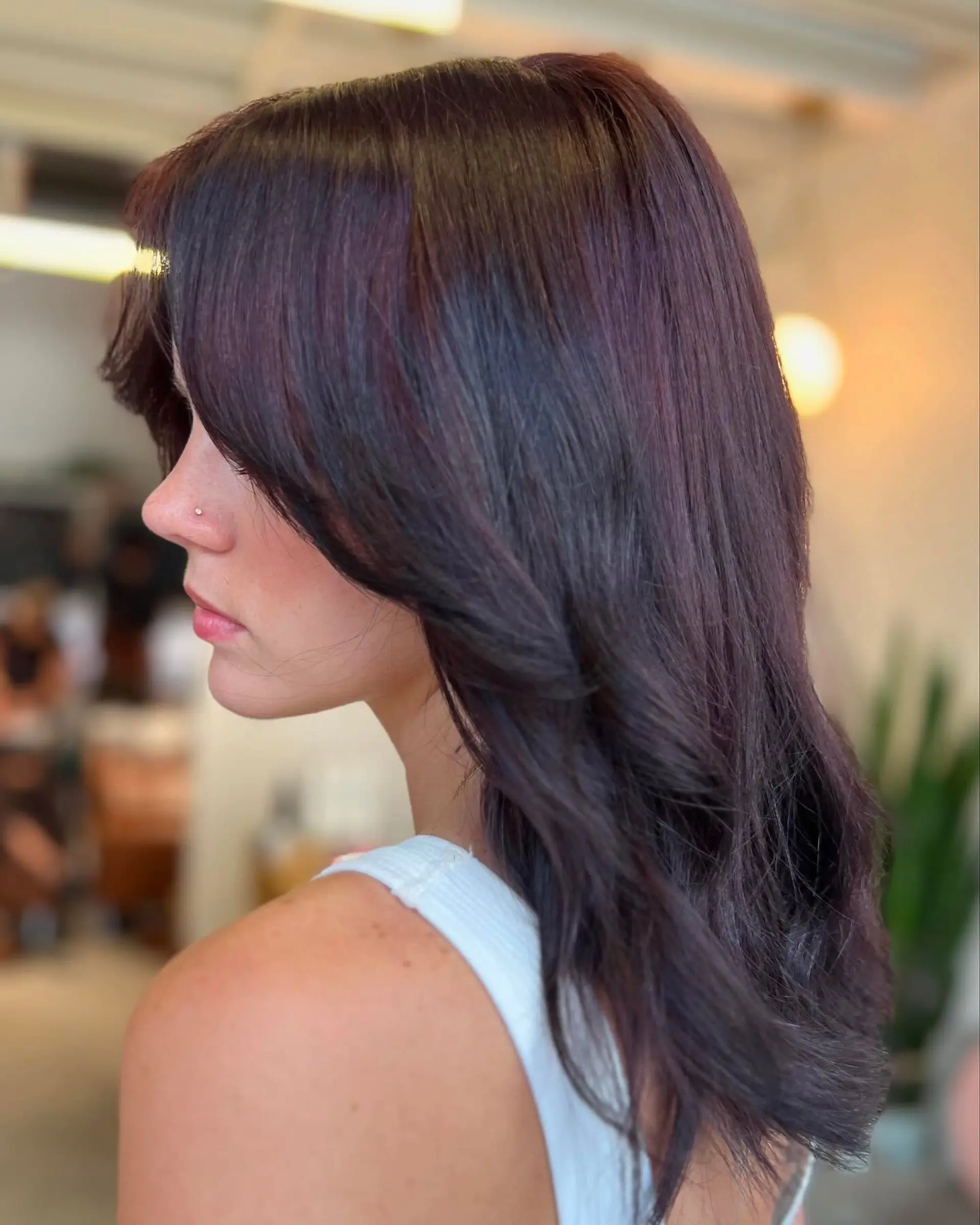 Medium-length dark cherry layered cut styled in a smooth blowout with sweeping curtain bangs. 1
