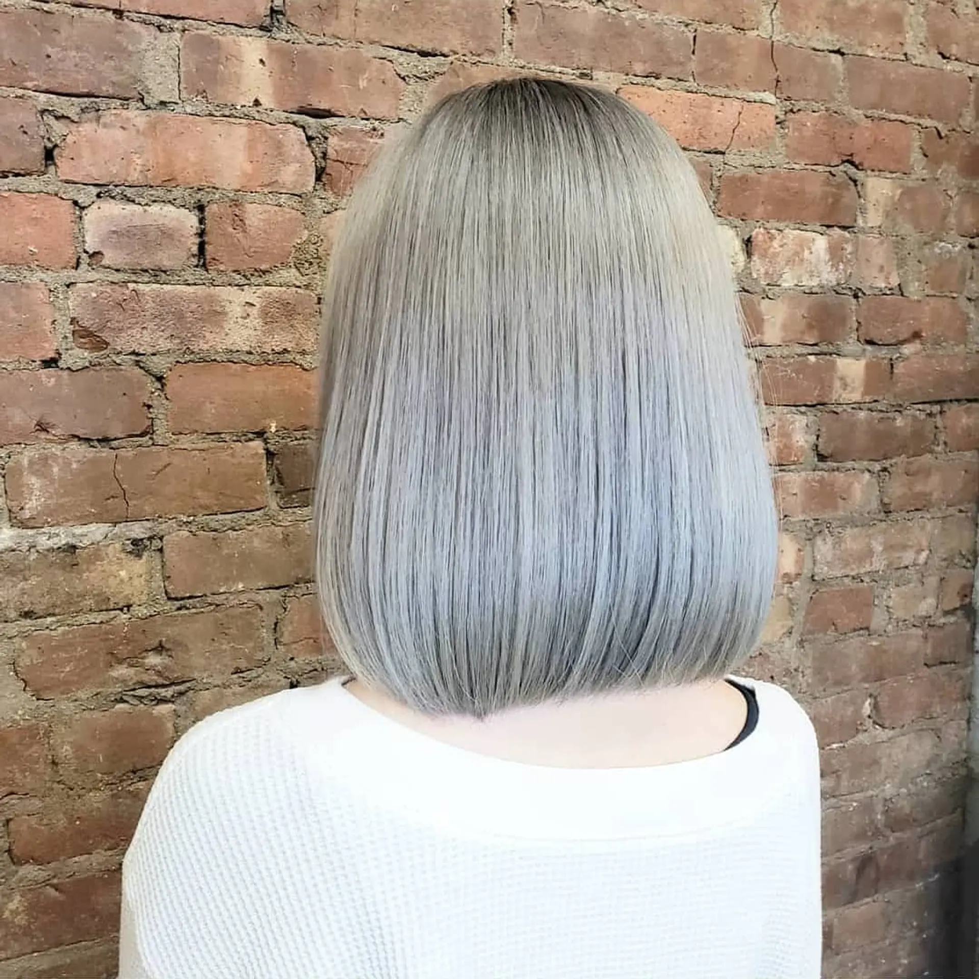 A sleek, blunt-cut bob featuring a seamless all-over icy silver tone with subtle root shadowing. 1