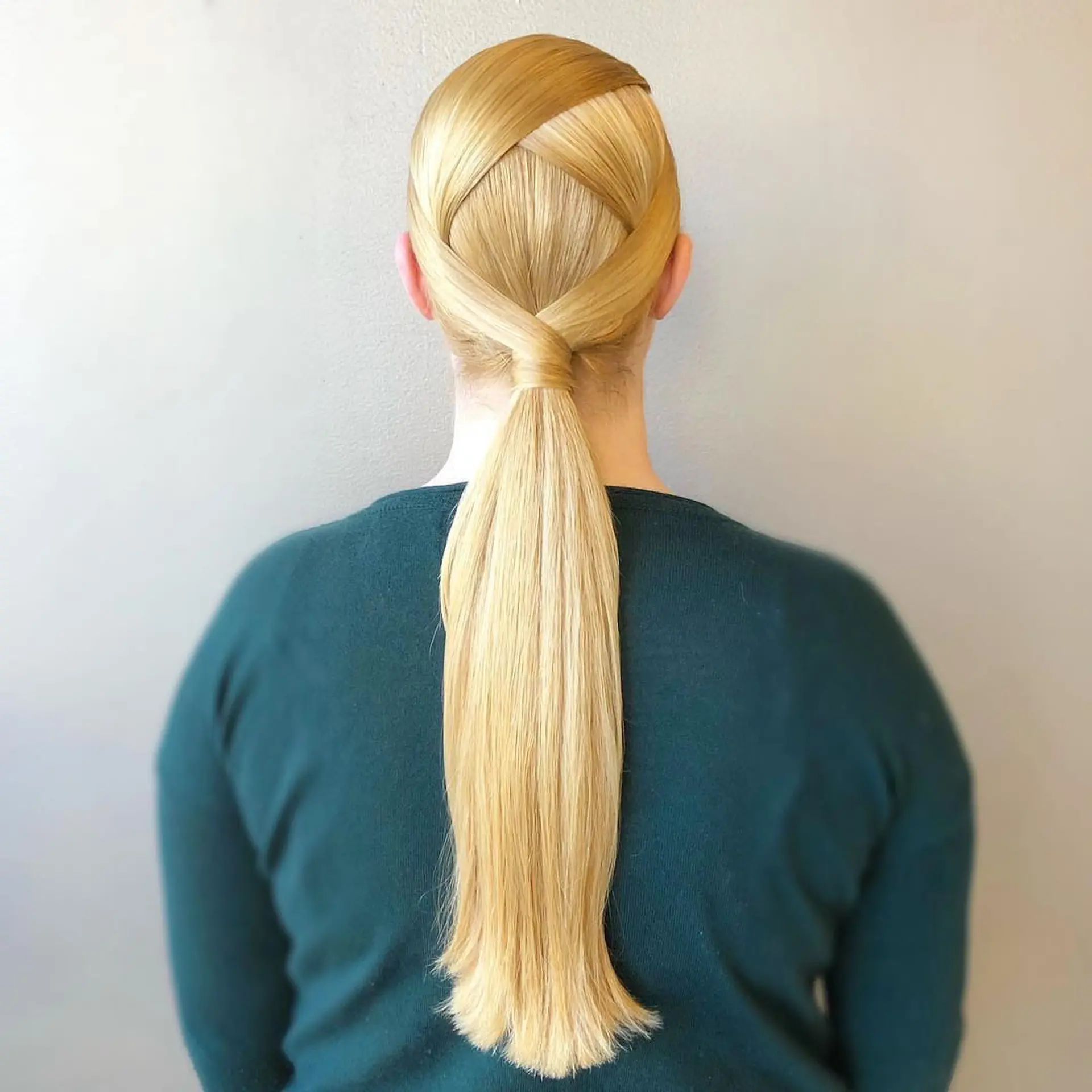 A sleek, geometric low ponytail featuring overlapping criss-cross sections neatly woven over the back of the head into a wrapped base. 1