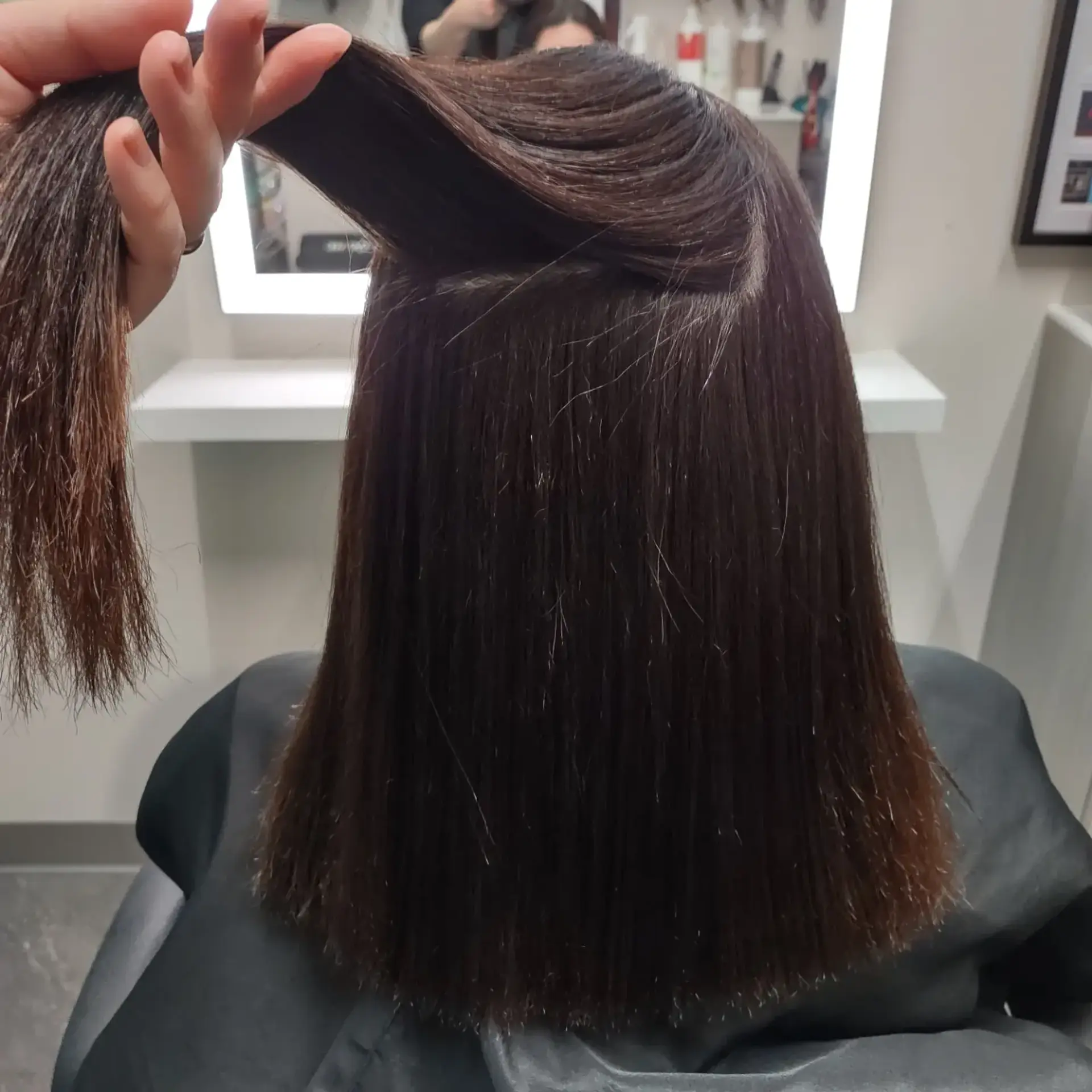 A sleek, glossy medium-length blunt cut showcasing pin-straight texture after a Japanese straightening retouch. 1
