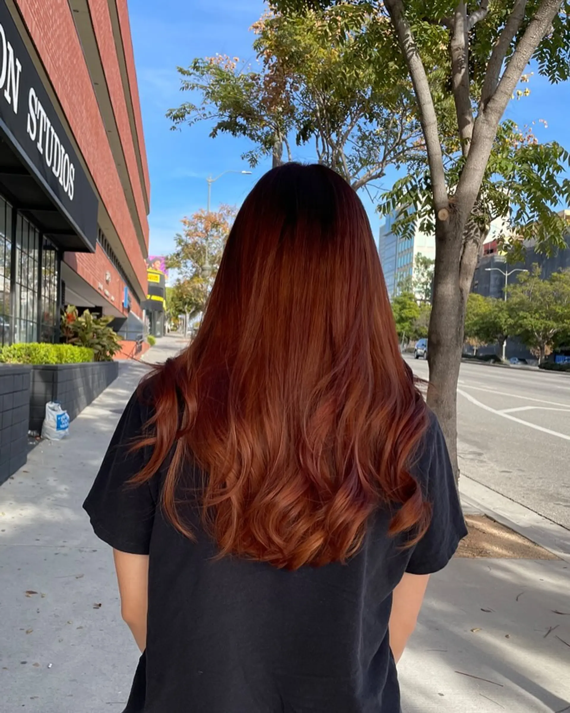 Rich copper-red balayage transitioning seamlessly from darker roots into vibrant, warm copper tones with soft waves at the ends. 1