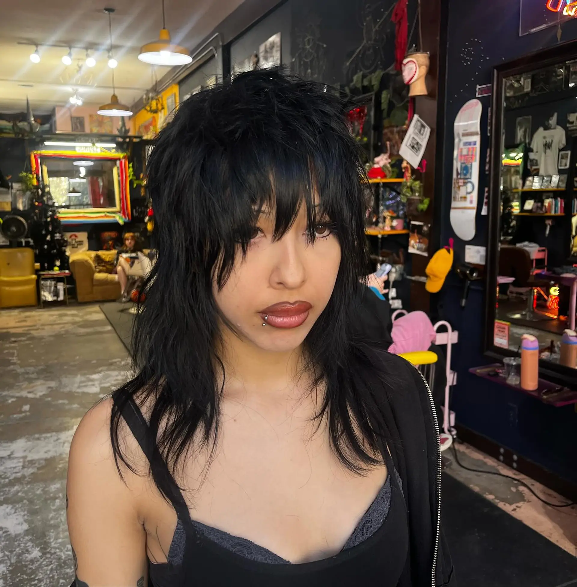A textured jet-black wolf cut featuring heavily layered volume at the crown, choppy face-framing pieces, and full piecey bangs. 1