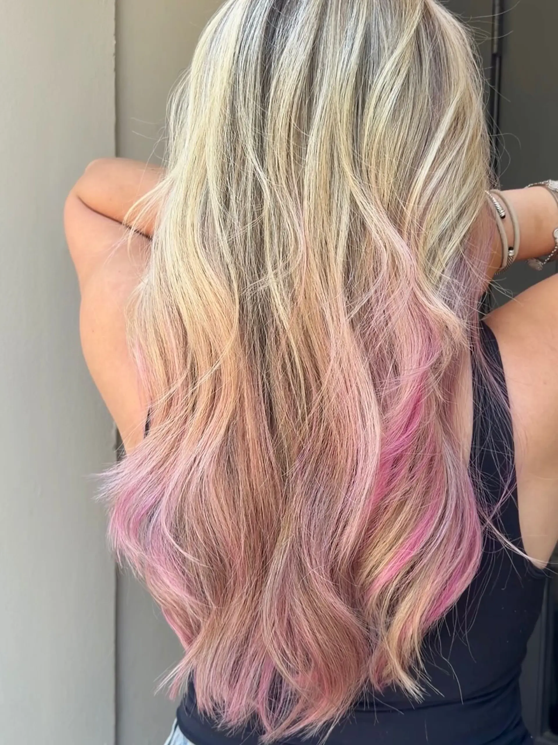 Long blonde hair styled in loose beach waves with vibrant pastel pink peekaboo underlights. 1