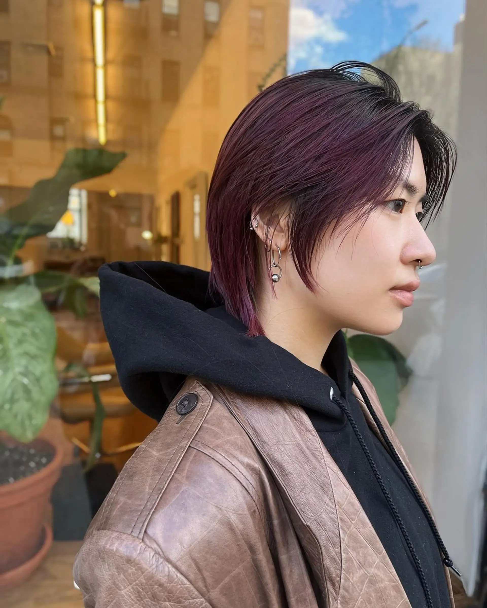 A chic and edgy short hairstyle with a layered cut that falls to ear-length, featuring side-swept bangs. The hair color is dark brown with vibrant plum highlights. 1