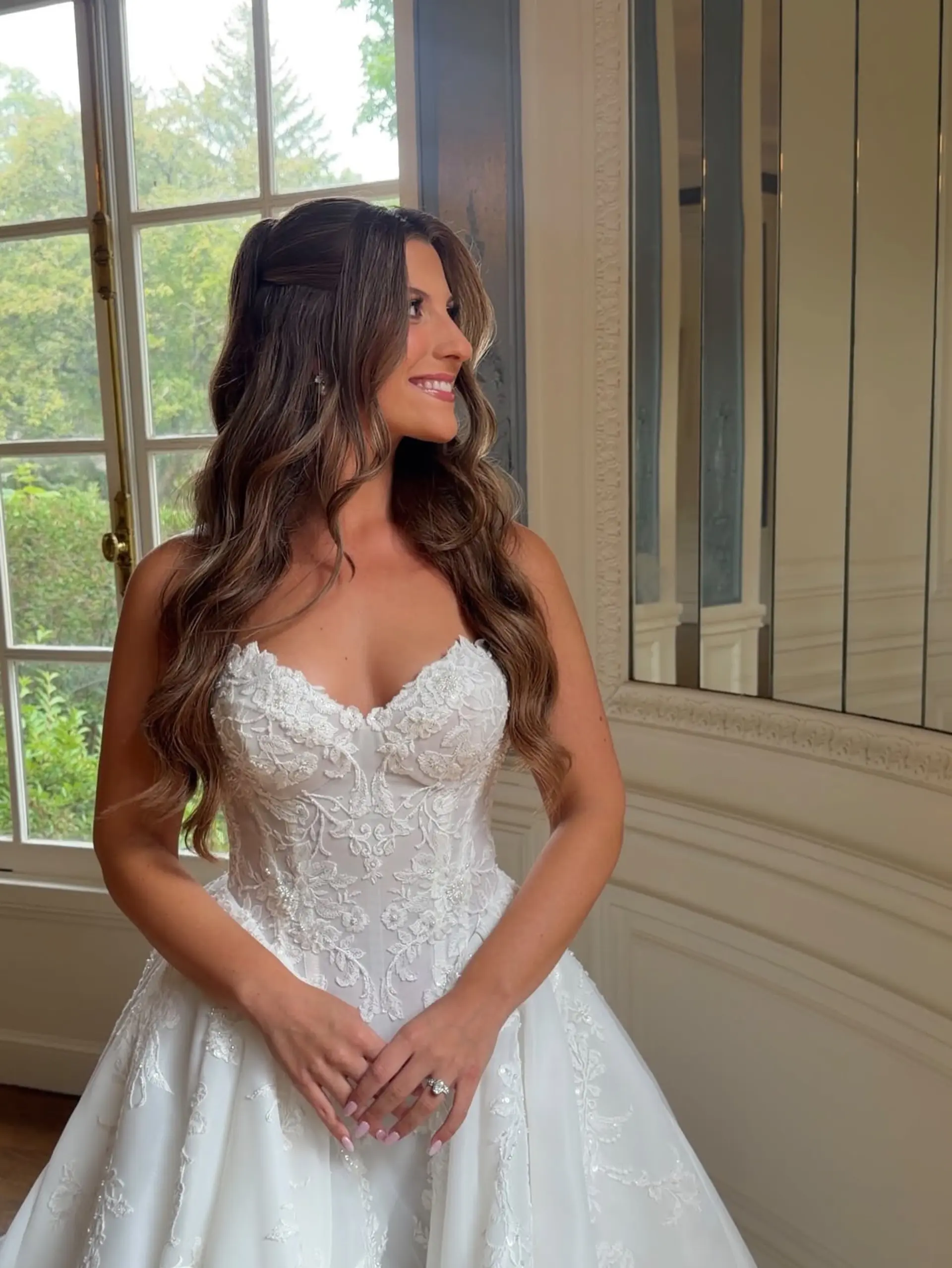 A romantic bridal half-up hairstyle with softly defined waves and seamless caramel balayage. 1