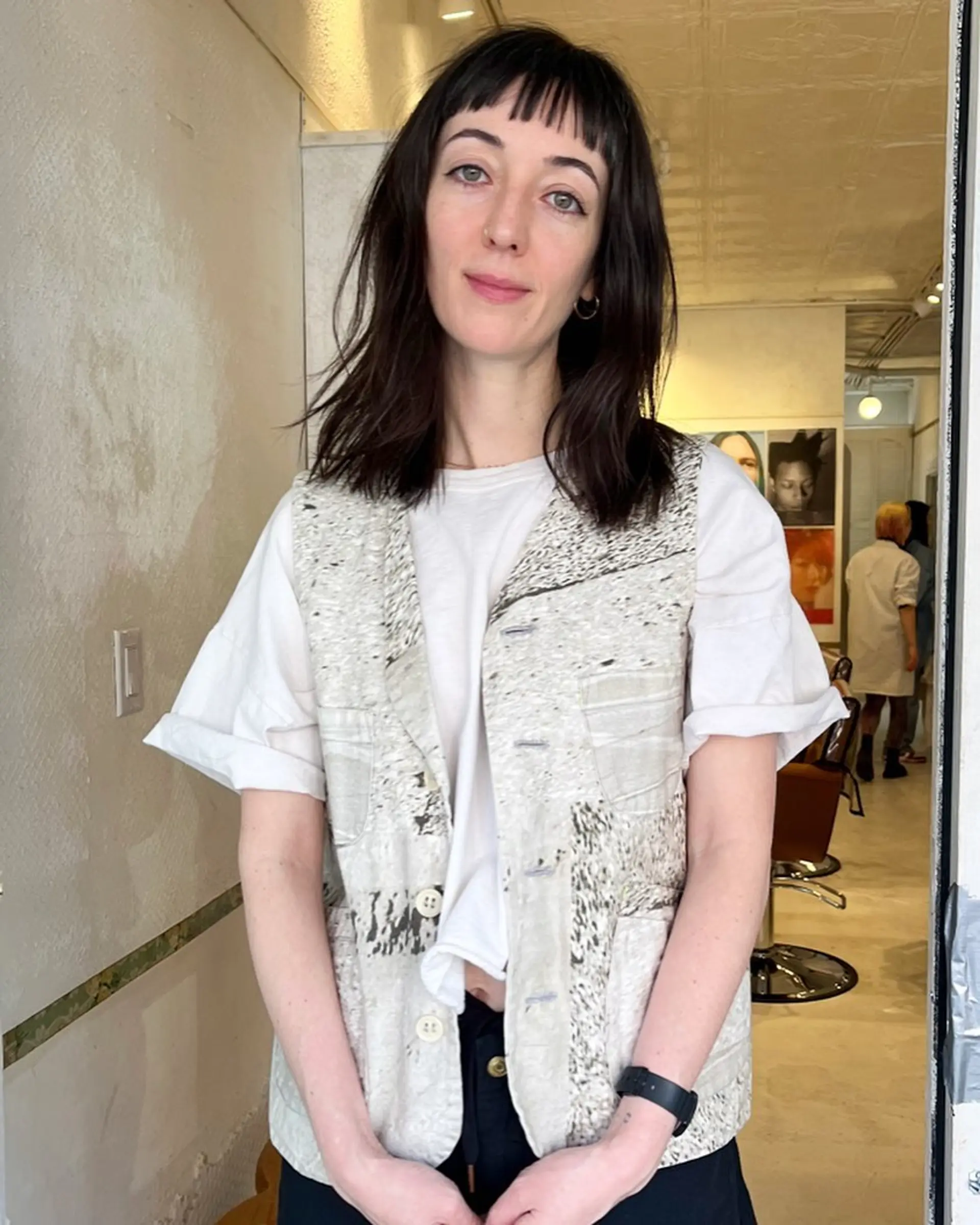 The hairstyle includes medium-length straight hair with blunt bangs and textured layers for a sleek, versatile look. 1