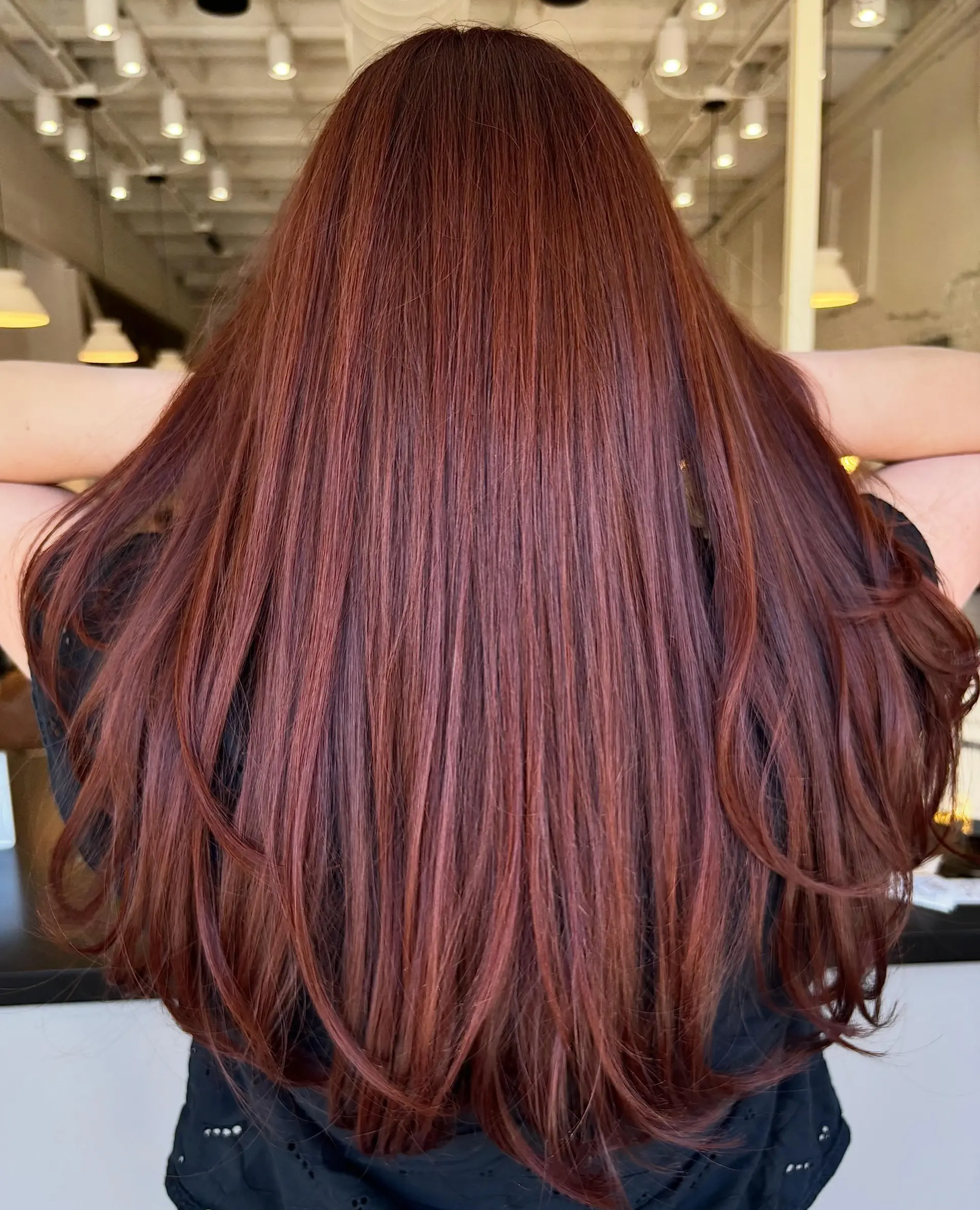 Long, glossy auburn-red hair styled straight with soft curled ends. 1