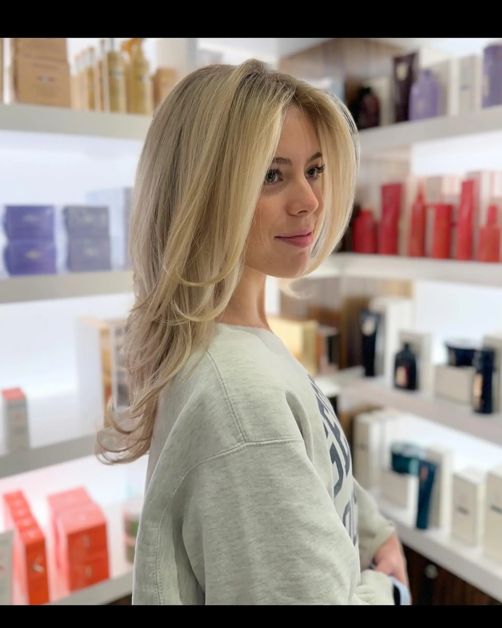 A voluminous blowout featuring feathered face-framing layers and soft curved ends on light blonde hair. 1