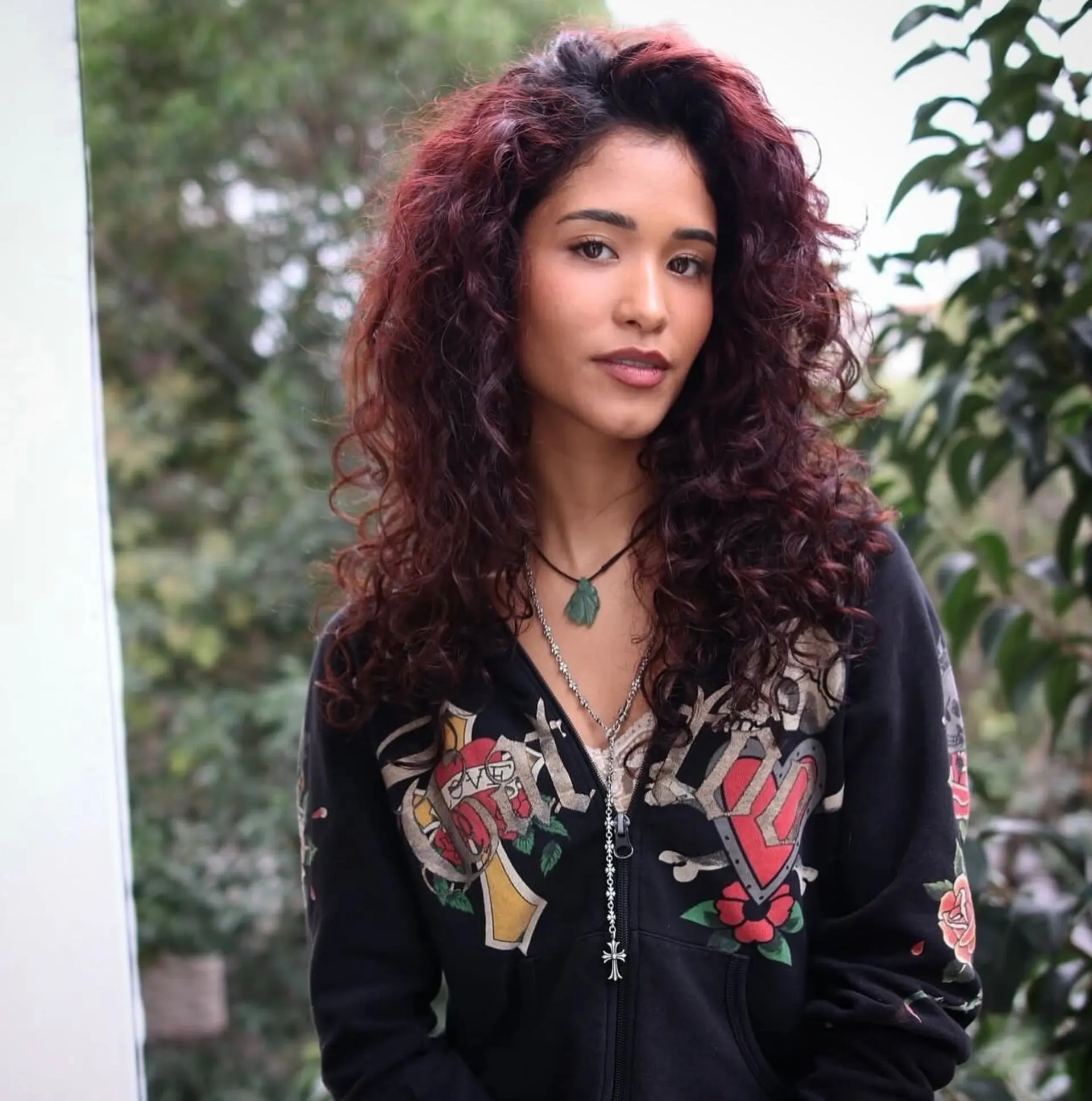 Medium-to-long voluminous curls cut in soft layers with deep auburn-burgundy tones and a defined, textured finish. 1