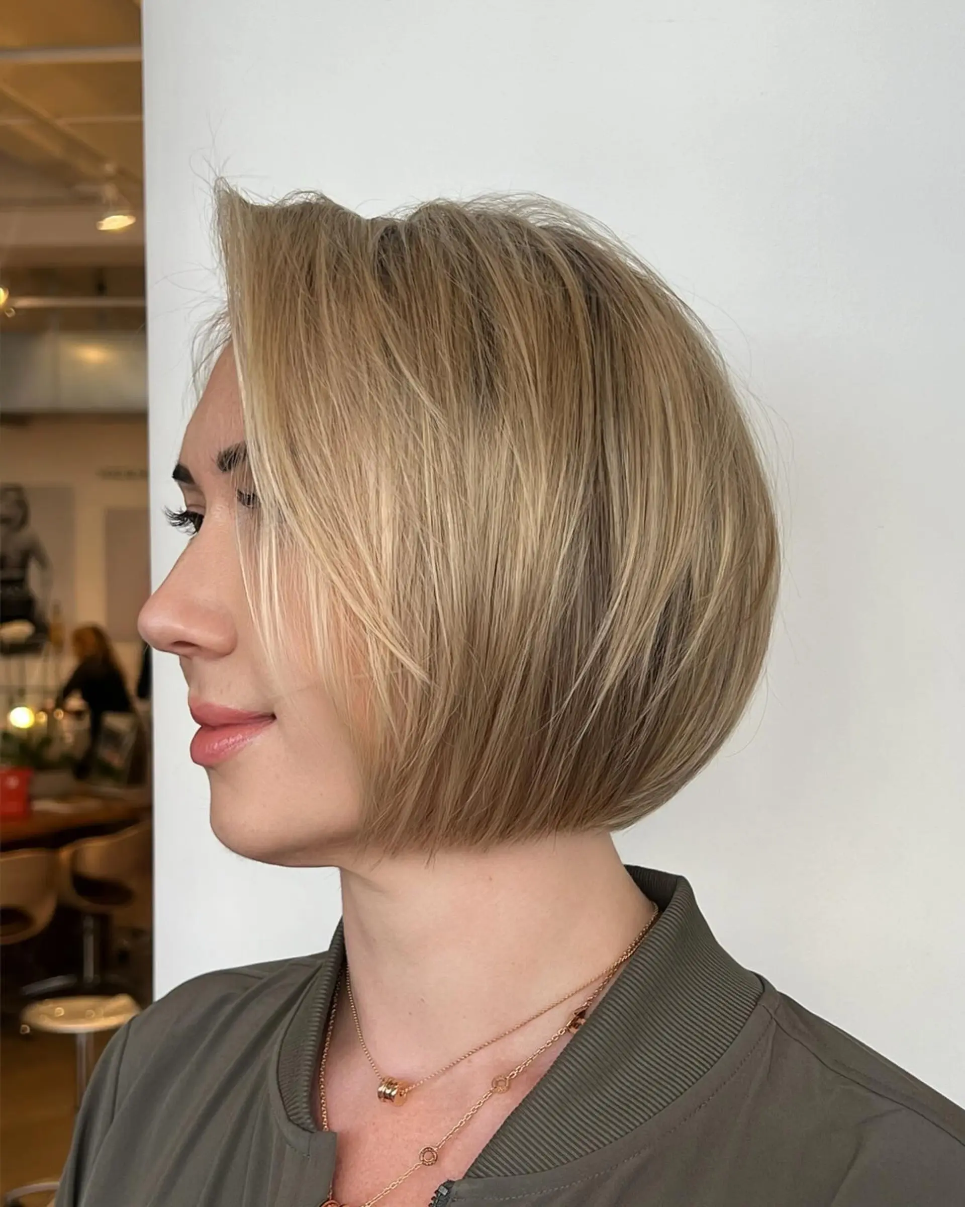A sleek, chin-length rounded bob haircut featuring soft dimensional blonde highlights and beveled ends. 1