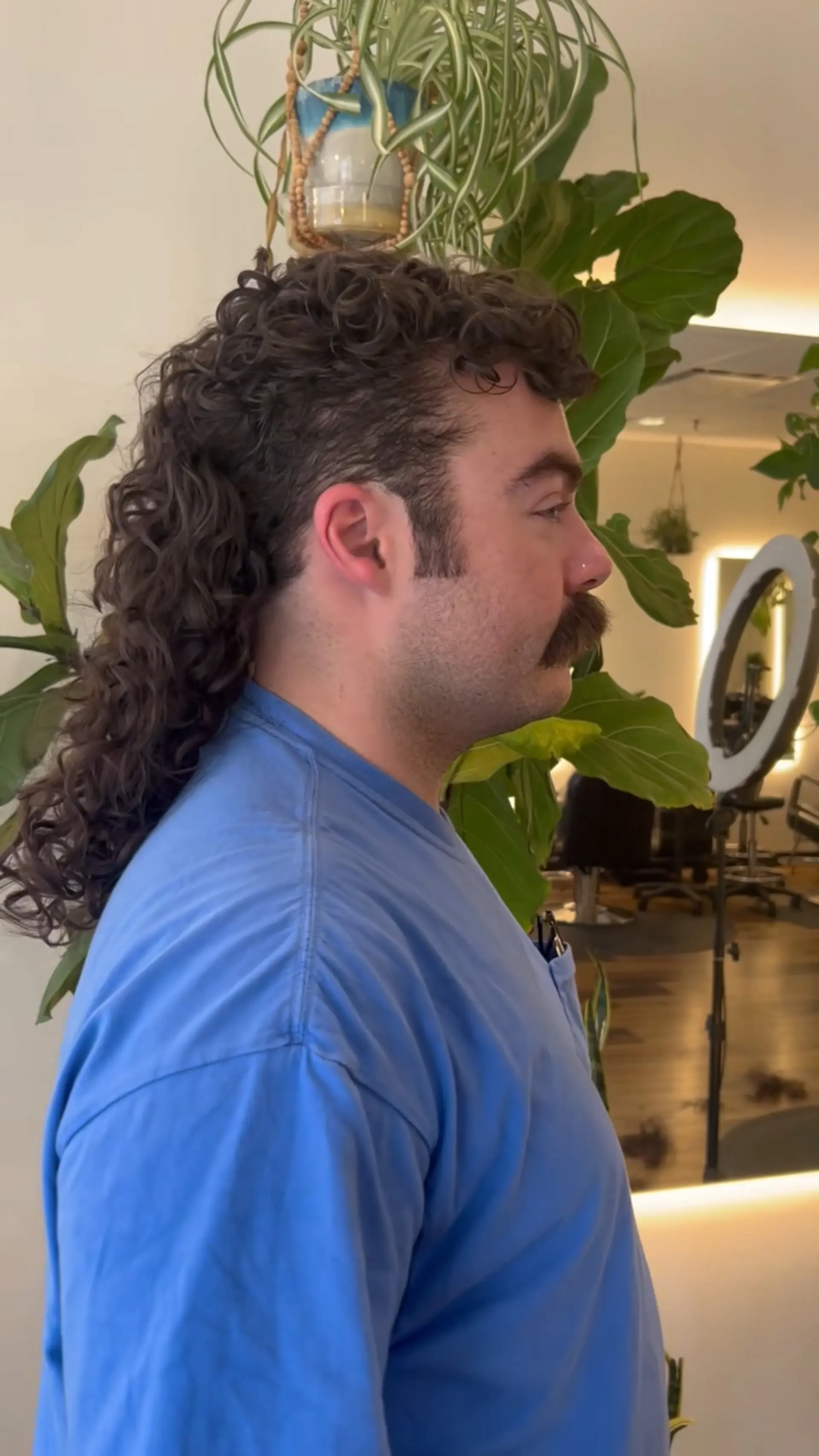 A modern curly mullet with cropped sides, textured curls on top, and defined curls flowing down the back. 1