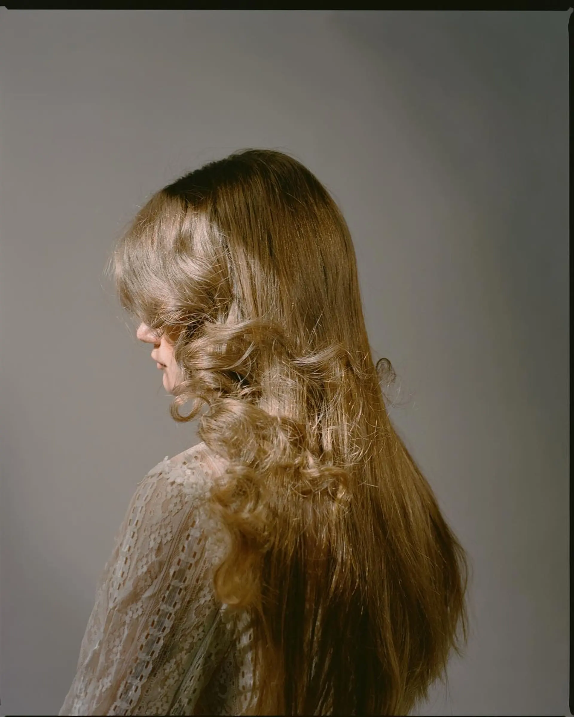 This hairstyle features long, wavy hair with soft curls starting midway, creating volume and a cascading effect with gentle golden highlights. 1