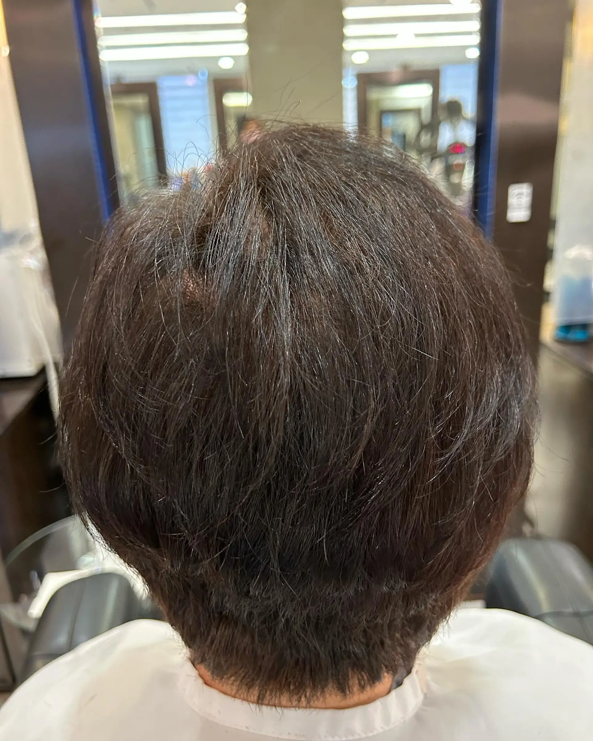 A textured short layered crop with natural body and root lift viewed from the back. 1