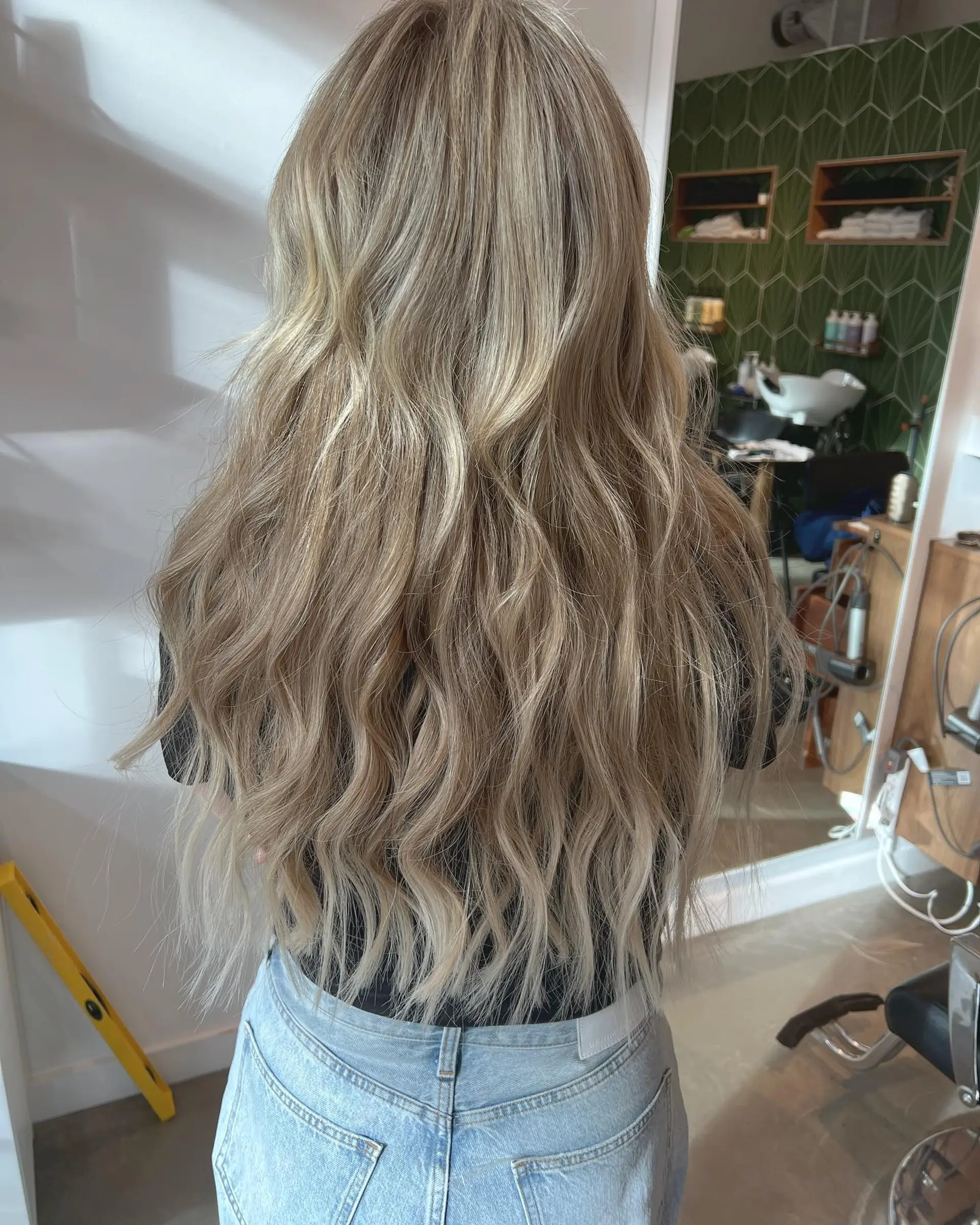 Extra-long dimensional ash blonde hair styled in relaxed, textured waves featuring seamless volume. 1