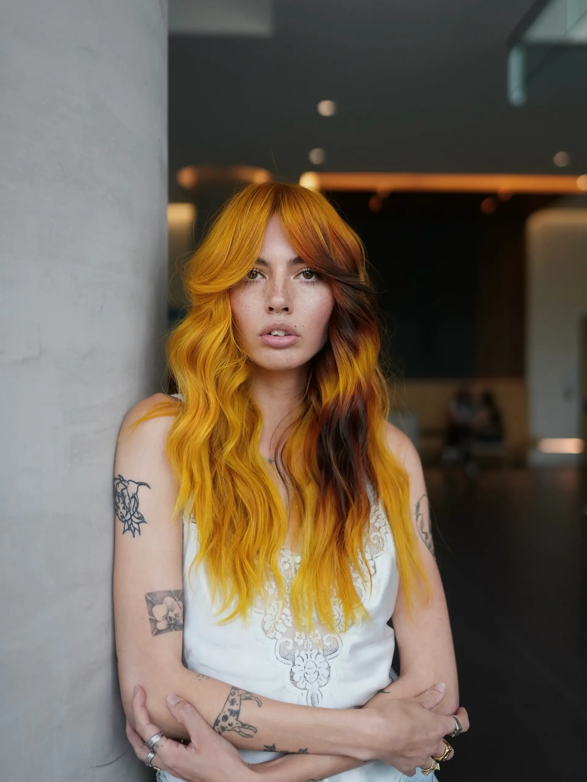 Vibrant marigold yellow and warm burnt orange long hair styled in loose retro waves with curtain bangs and contrasting dark undertones. 1