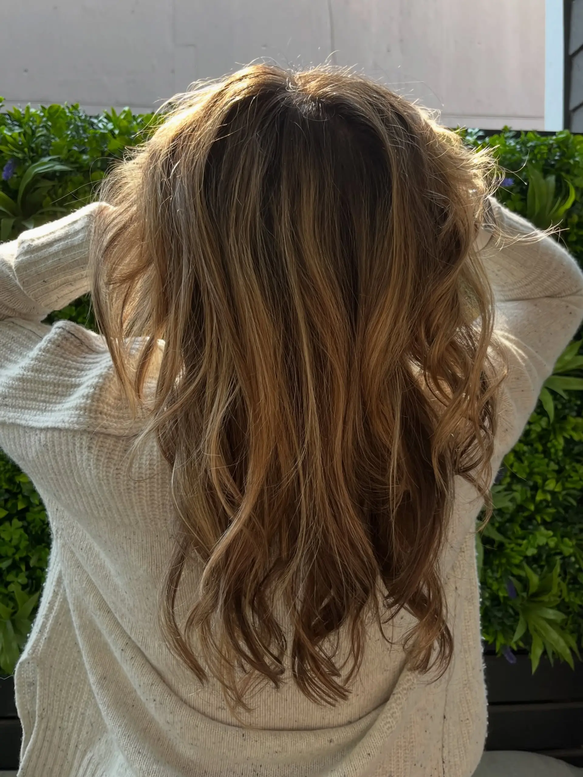 Long dimensional brunette hair with sun-kissed caramel highlights, styled into loose, effortless waves. 1