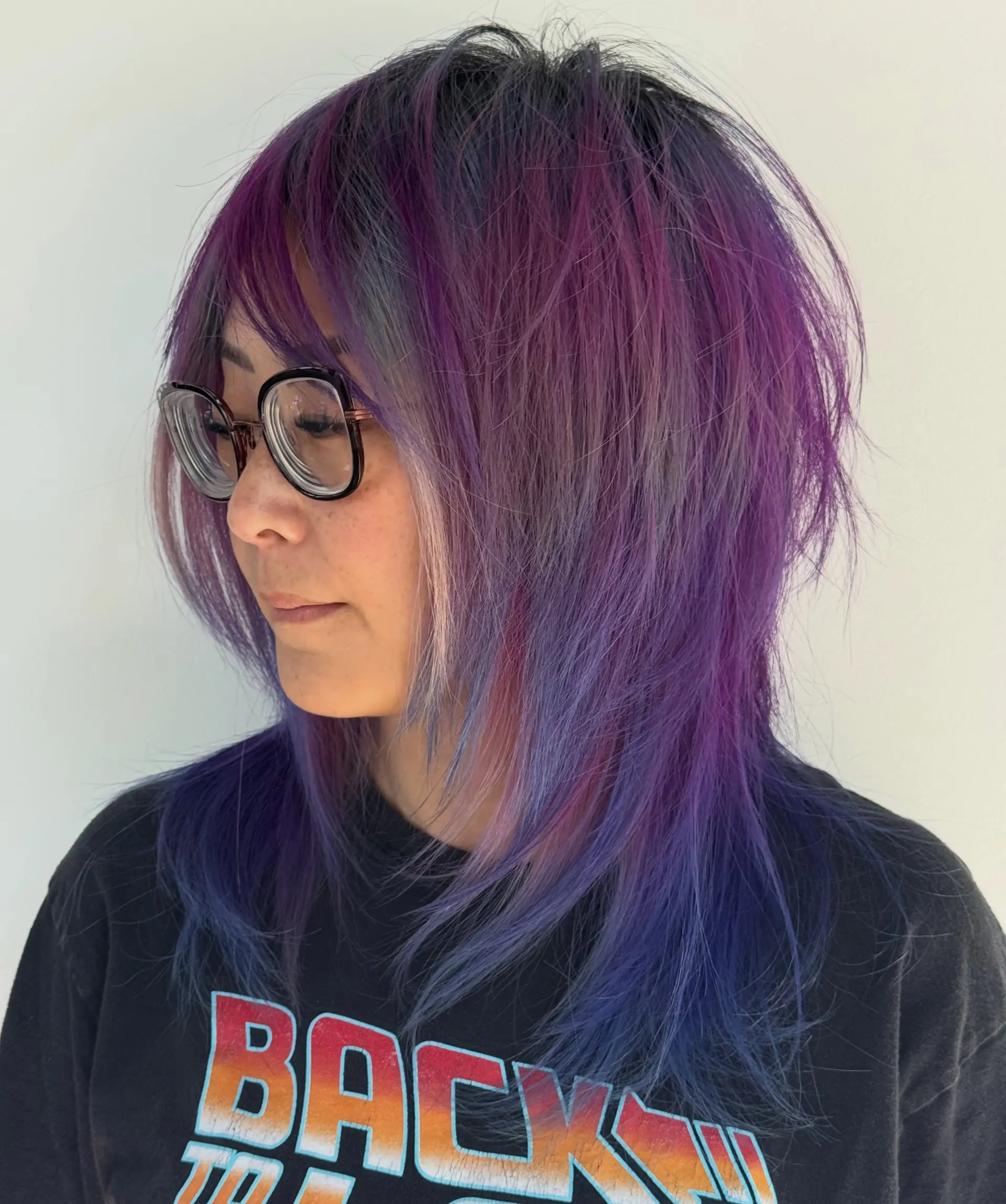 A medium-length textured shag with piecey fringe, heavily feathered face-framing layers, and multi-tonal purple hues. 1