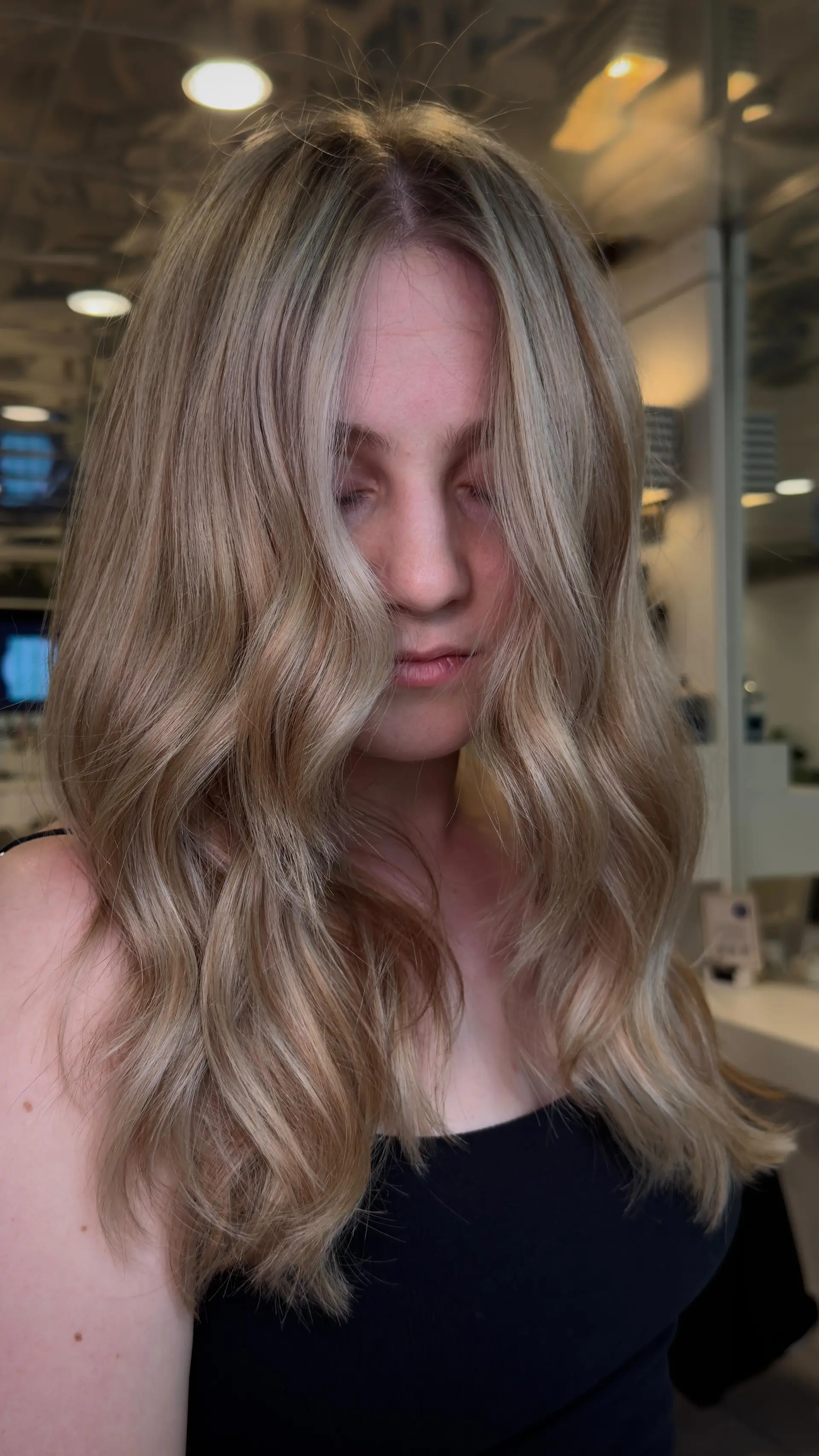 Long dimensional blonde hair styled into soft, flowing beach waves that fall around the face. 1
