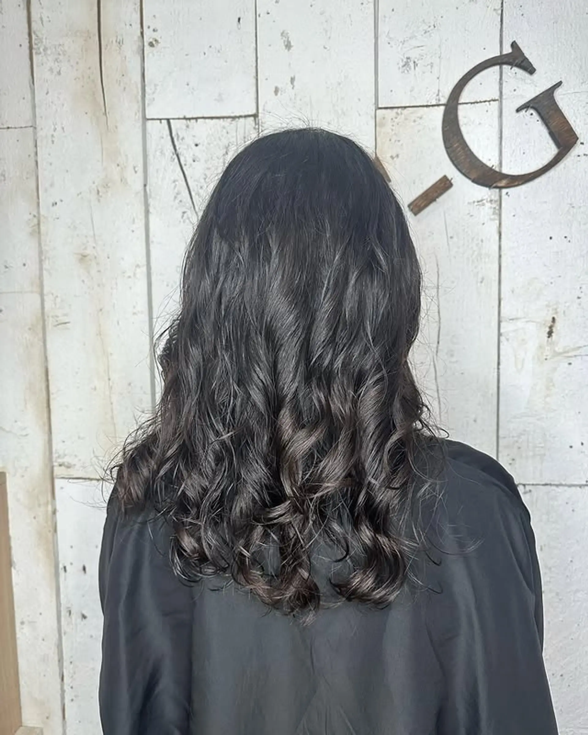 A layered curly hairstyle with natural waves that enhance volume and movement. 1