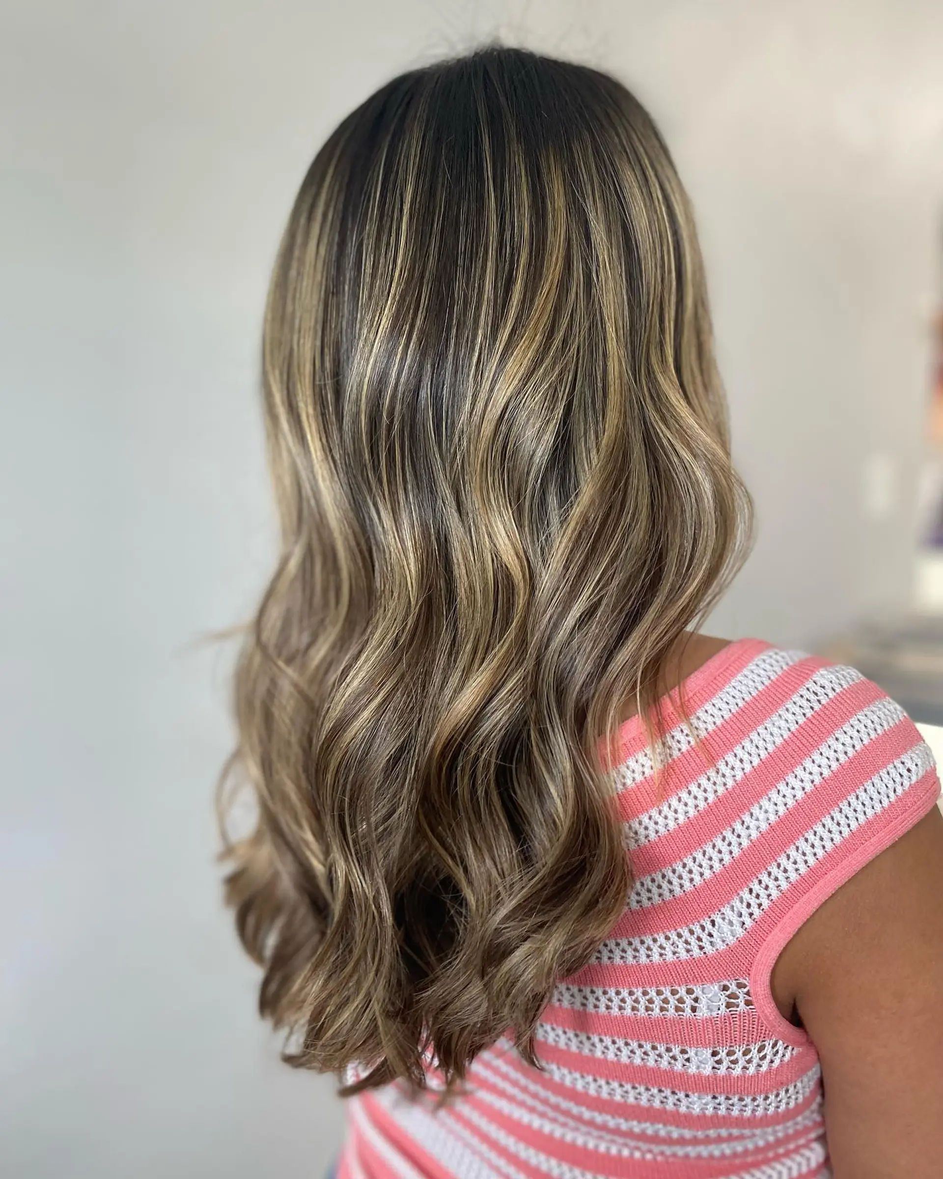 Long wavy hair with caramel ribbon balayage highlights for a trendy, dimensional look. 1
