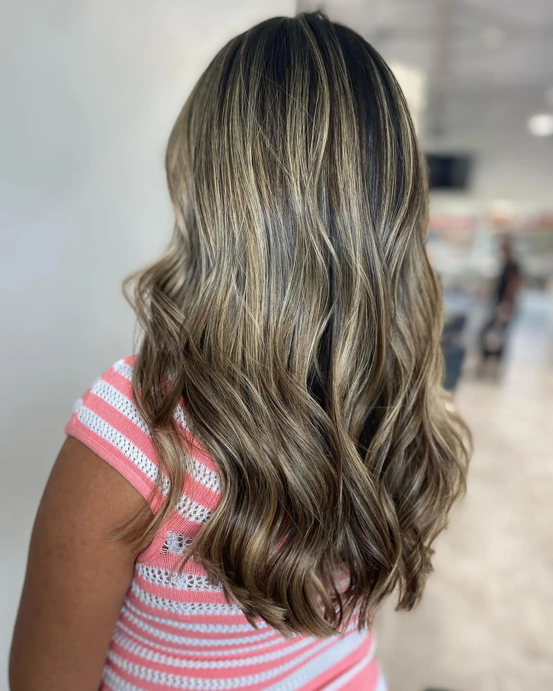 Long wavy hair with caramel ribbon balayage highlights for a trendy, dimensional look. 3
