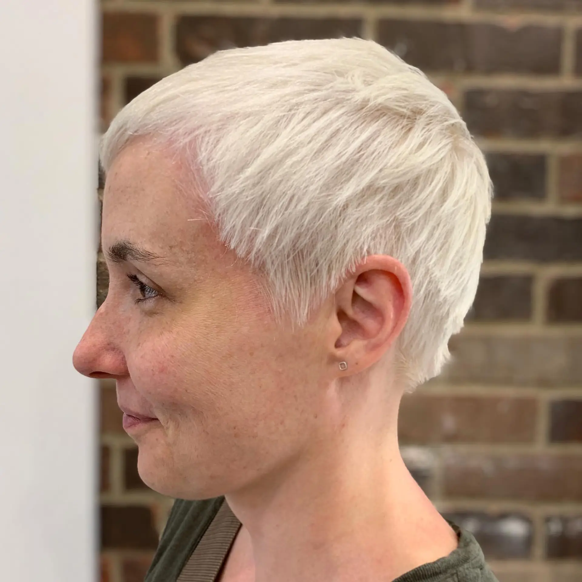 A textured icy platinum pixie cut styled with soft, wispy micro fringe and tapered sides. 1