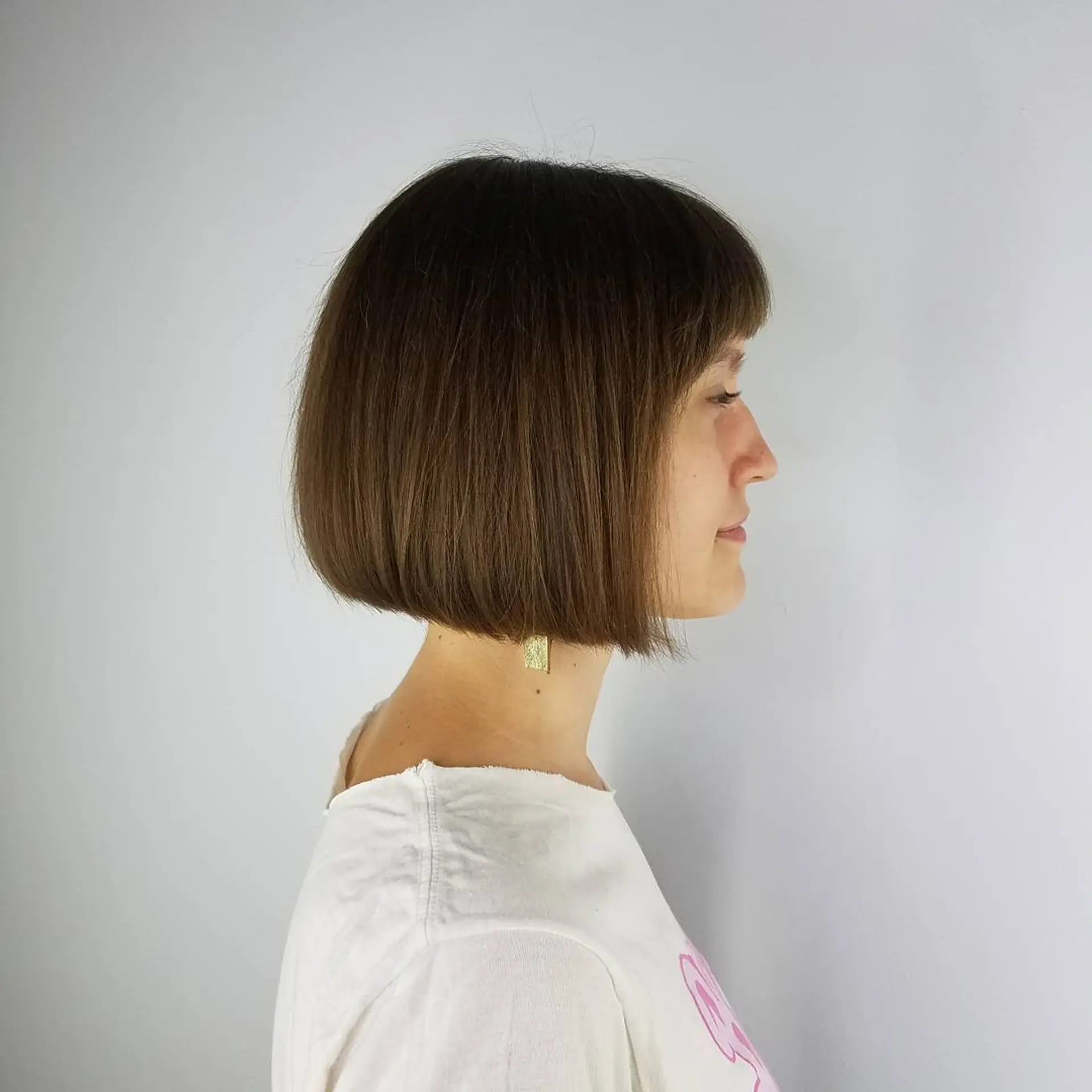 A sleek, chin-length blunt bob haircut paired with full straight bangs. 1