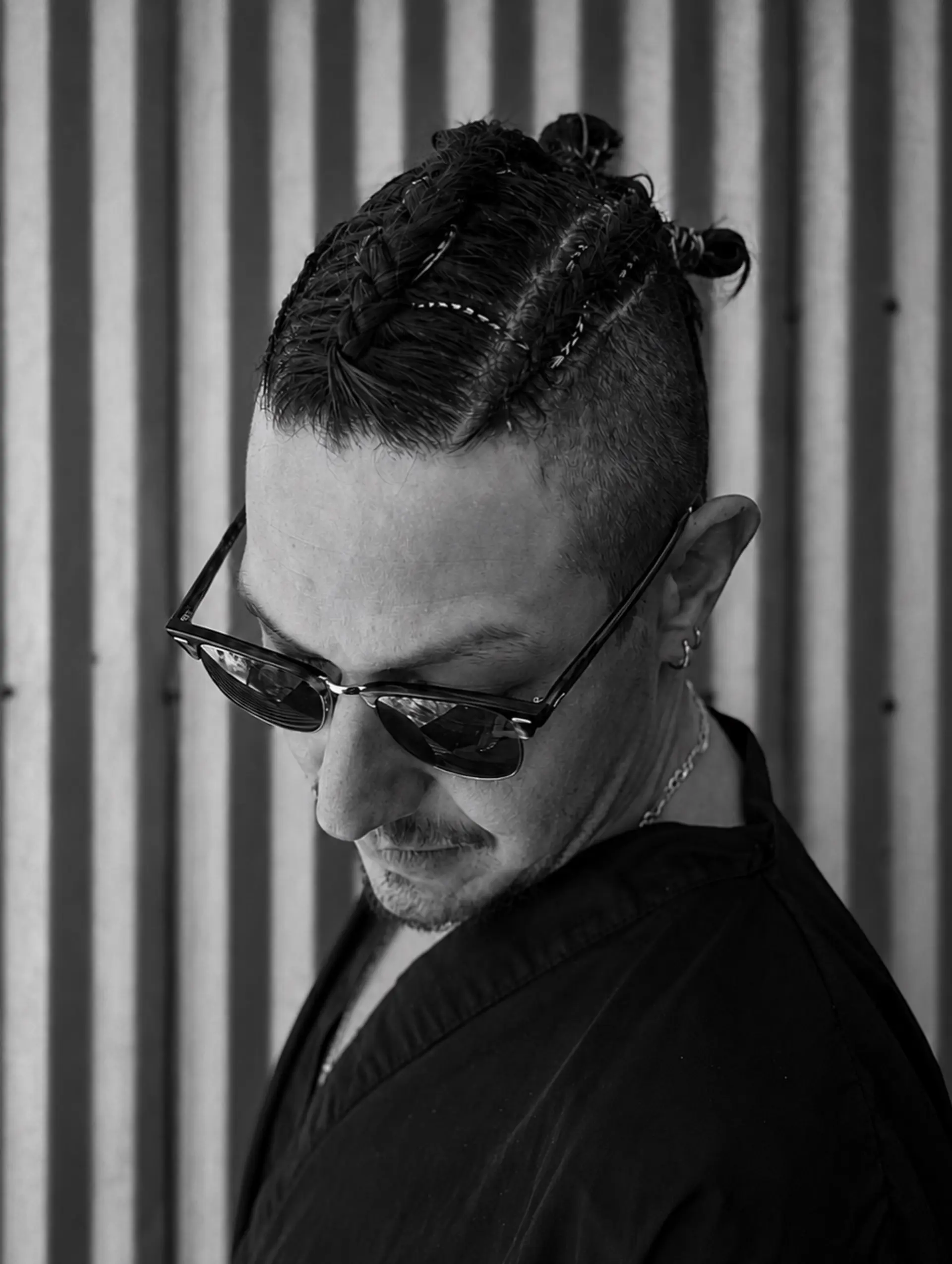 A men's undercut featuring clean faded sides and tight cornrow braids on top gathered into small knots at the back. Estimate scope: Haircut component only, from $85. Cornrow braiding/top-knot styling is not priced by the selected Gentleman's Cut mapping. Do not label $85 as the complete braided-look total; braiding and finishing scope/price remain unknown. 1