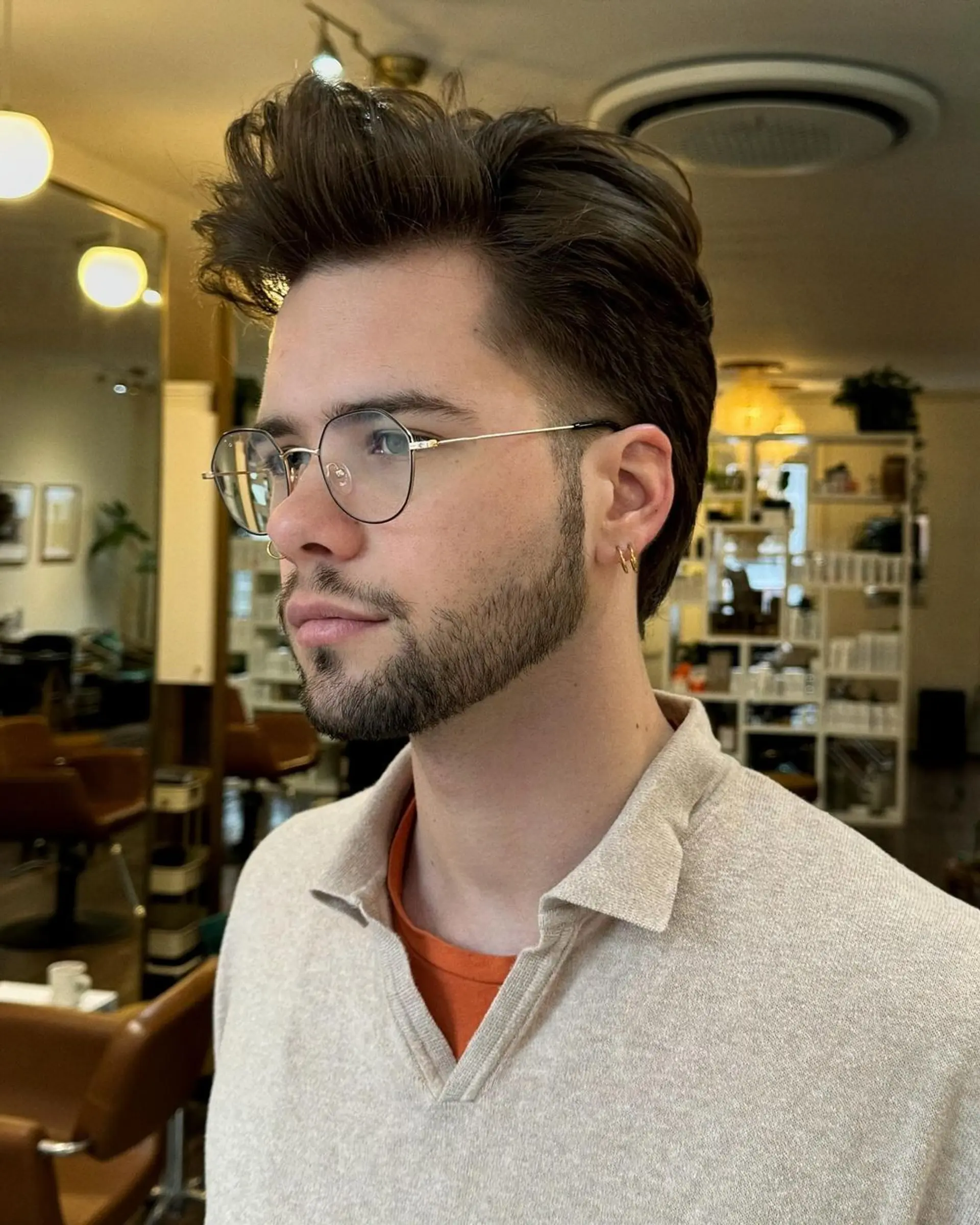 A voluminous wavy pompadour with styled height and tapered sides, featuring textured dark brown layers for a sleek, retro-inspired finish. 1