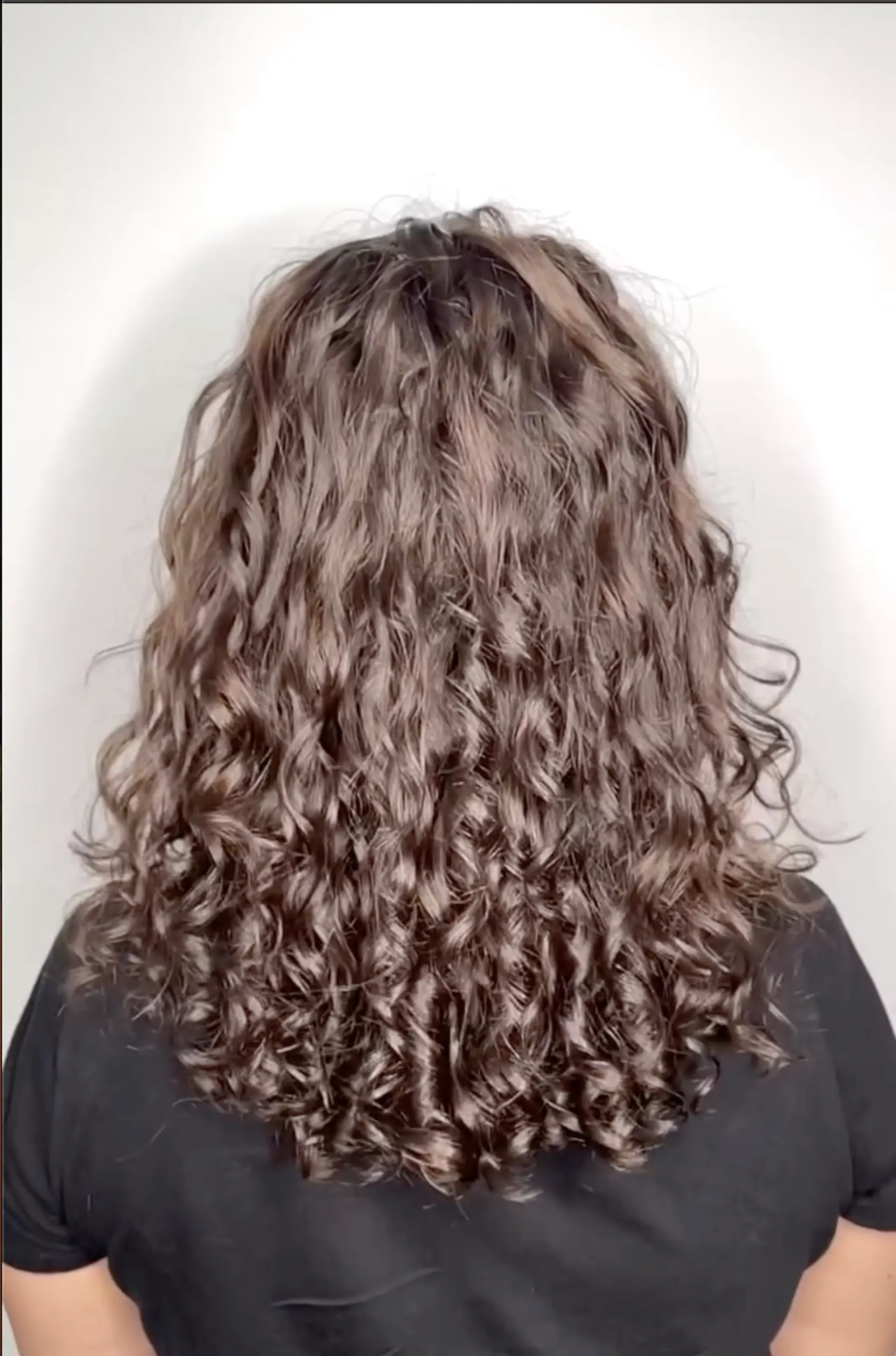 Medium-length dark brown curly hair with a voluminous and bouncy texture that cascades down to the shoulders. 1