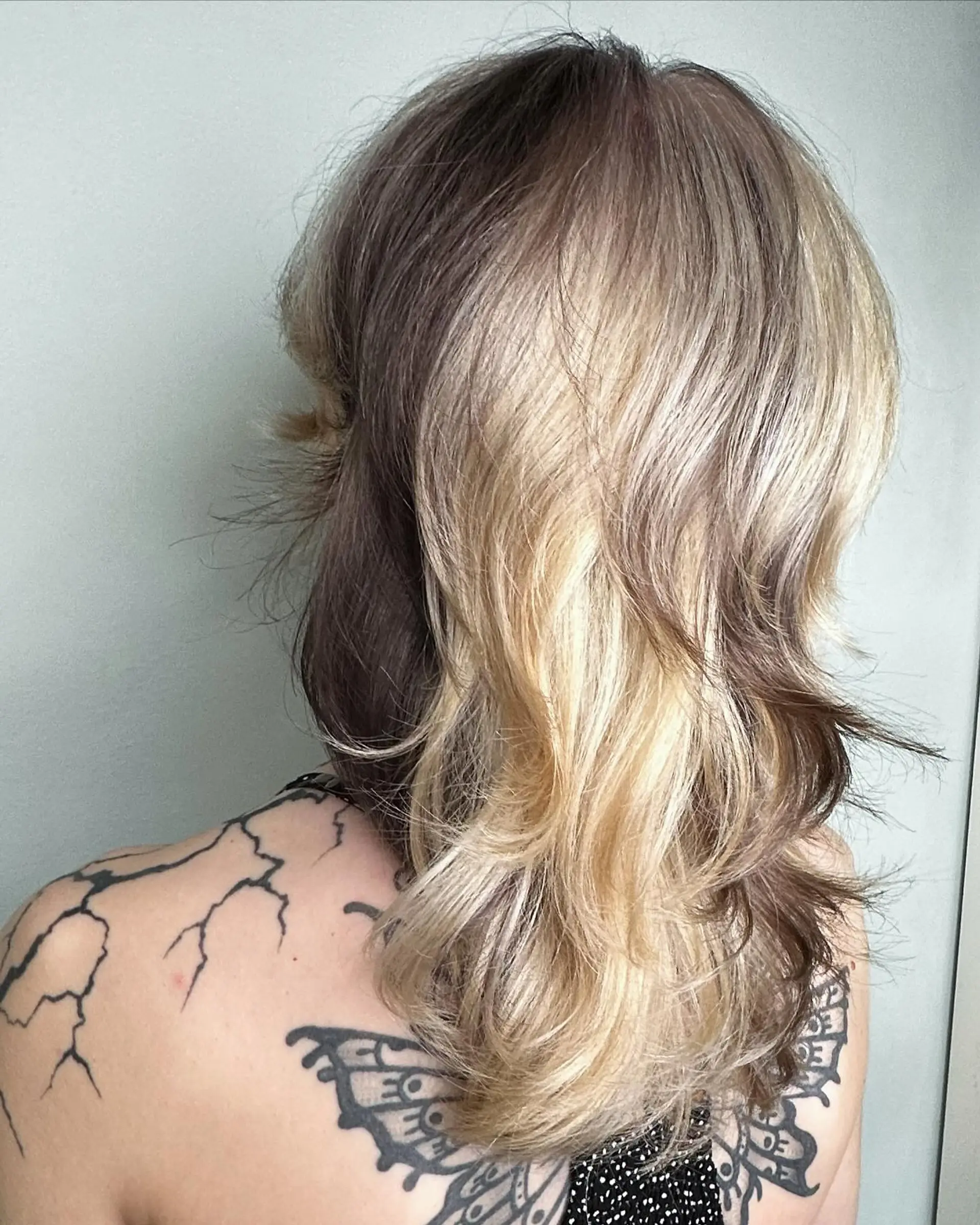 Medium-length wavy layered shag featuring bold color-blocked panels of blonde over deeper brunette tones. 1