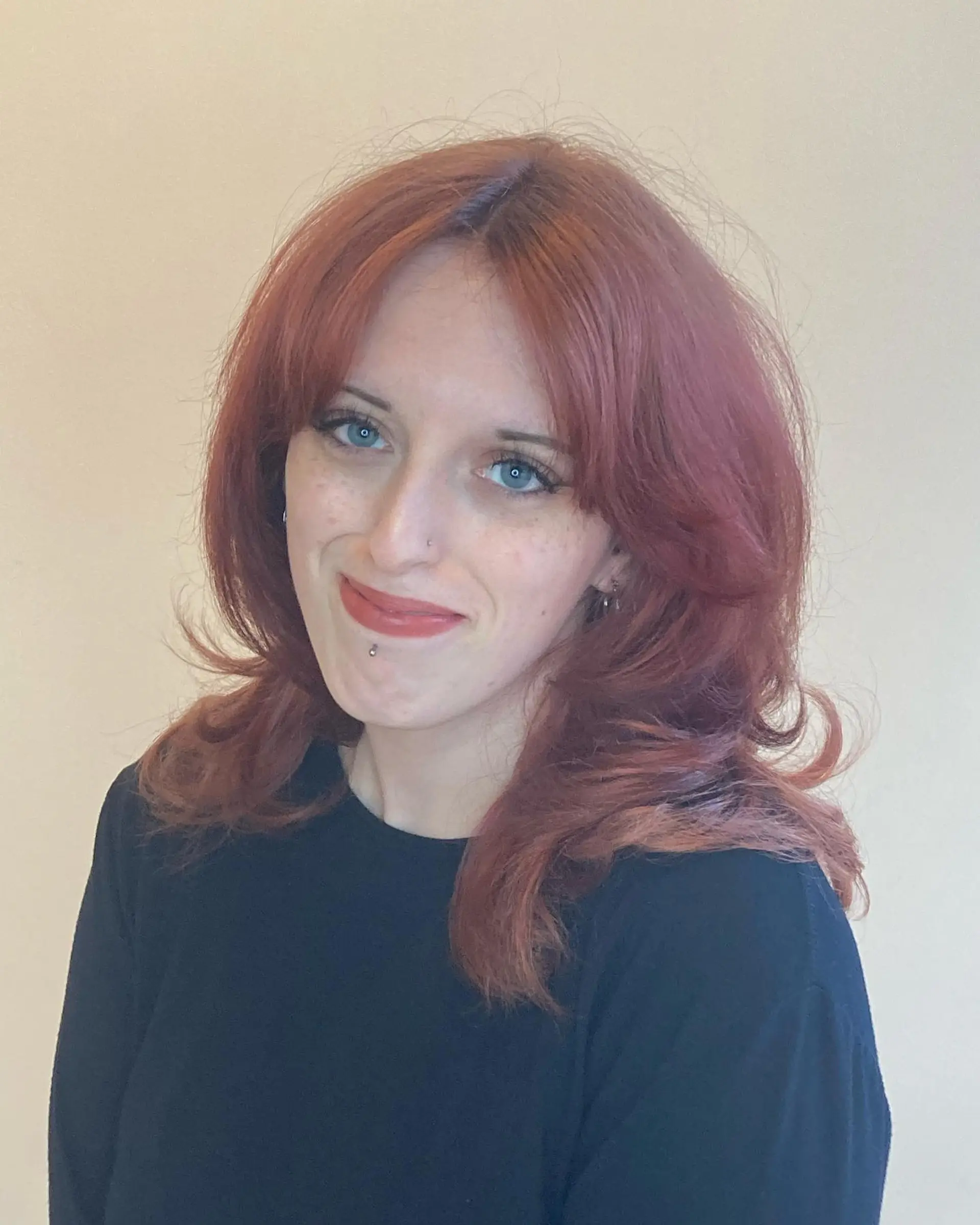 A medium-length cool-toned red shag haircut featuring curtain bangs and feathered face-framing layers. 1