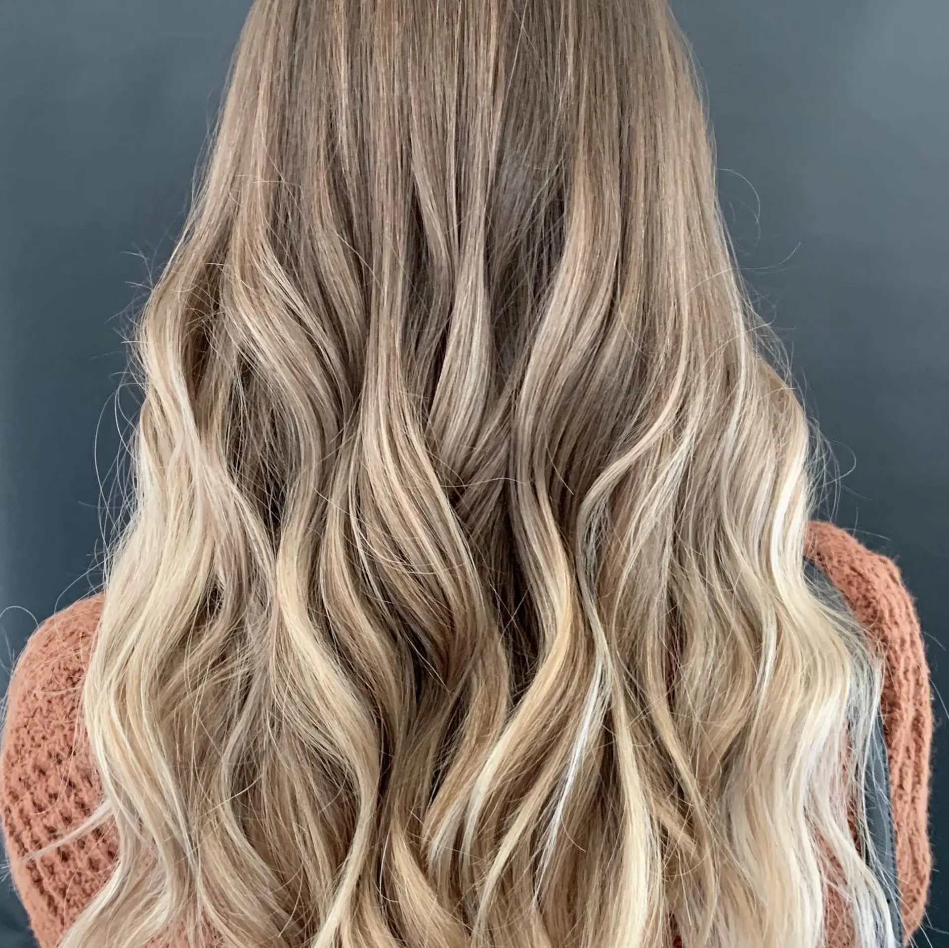 Long hair featuring a seamless blonde balayage with soft, loose textured waves. 1