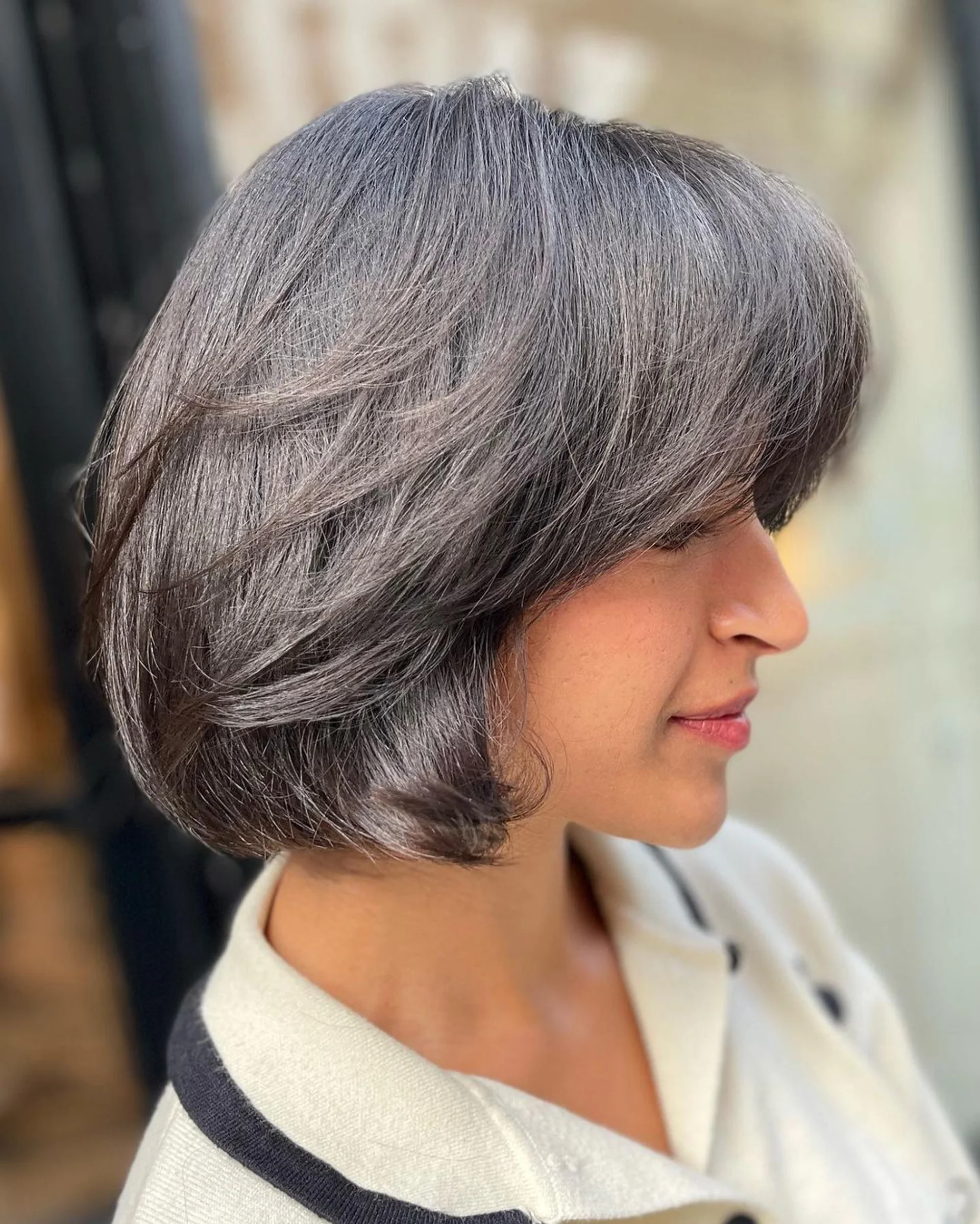 A model with a vibrant red, medium-length bob and sharp blunt bangs, showcasing the 2025 hair trend of Chromatic Courage. - Preview 3