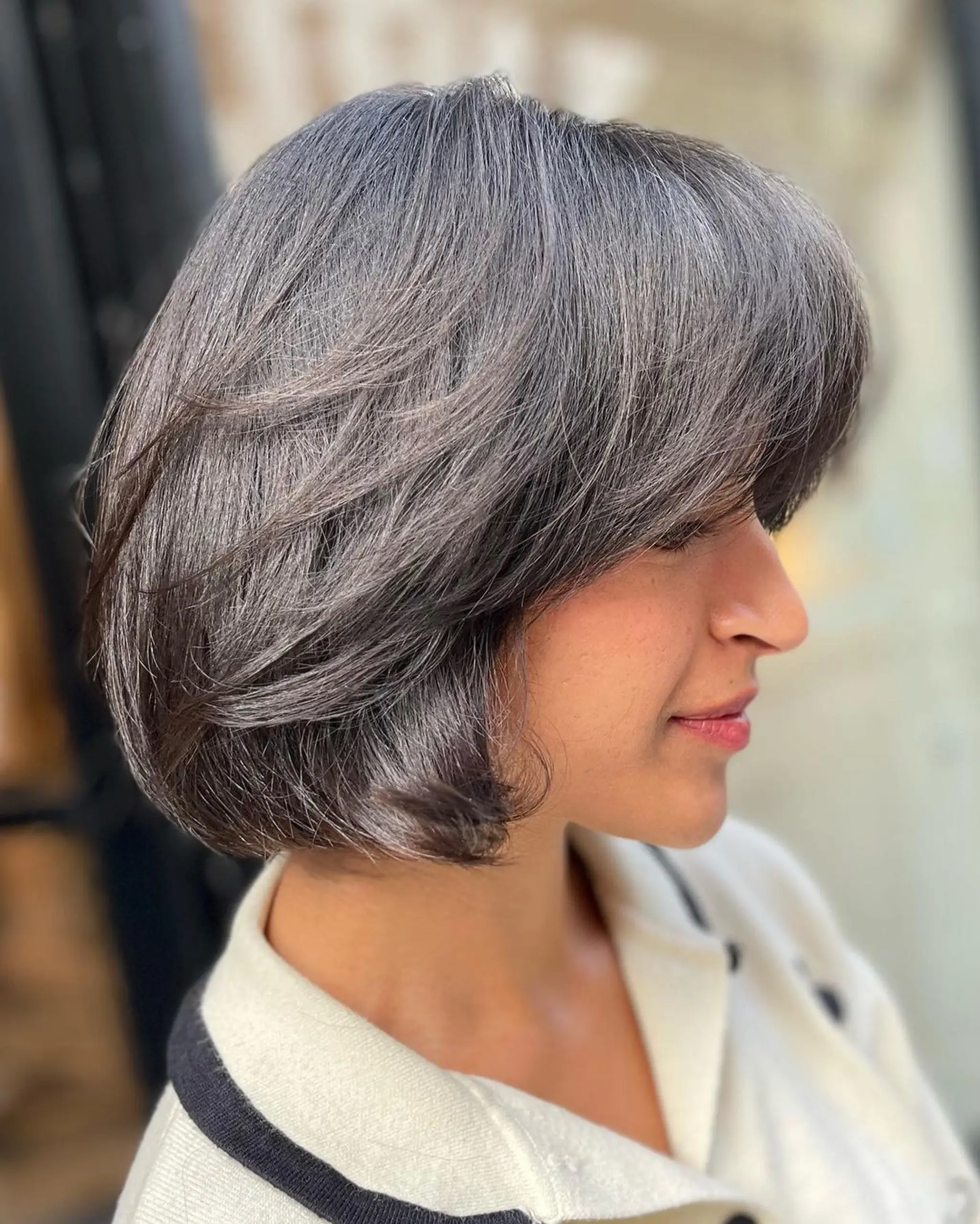 A stylish and modern short bob with a sophisticated blend of silver and grey. The straight hair features a side-swept fringe and layered sections for added movement and depth. 1