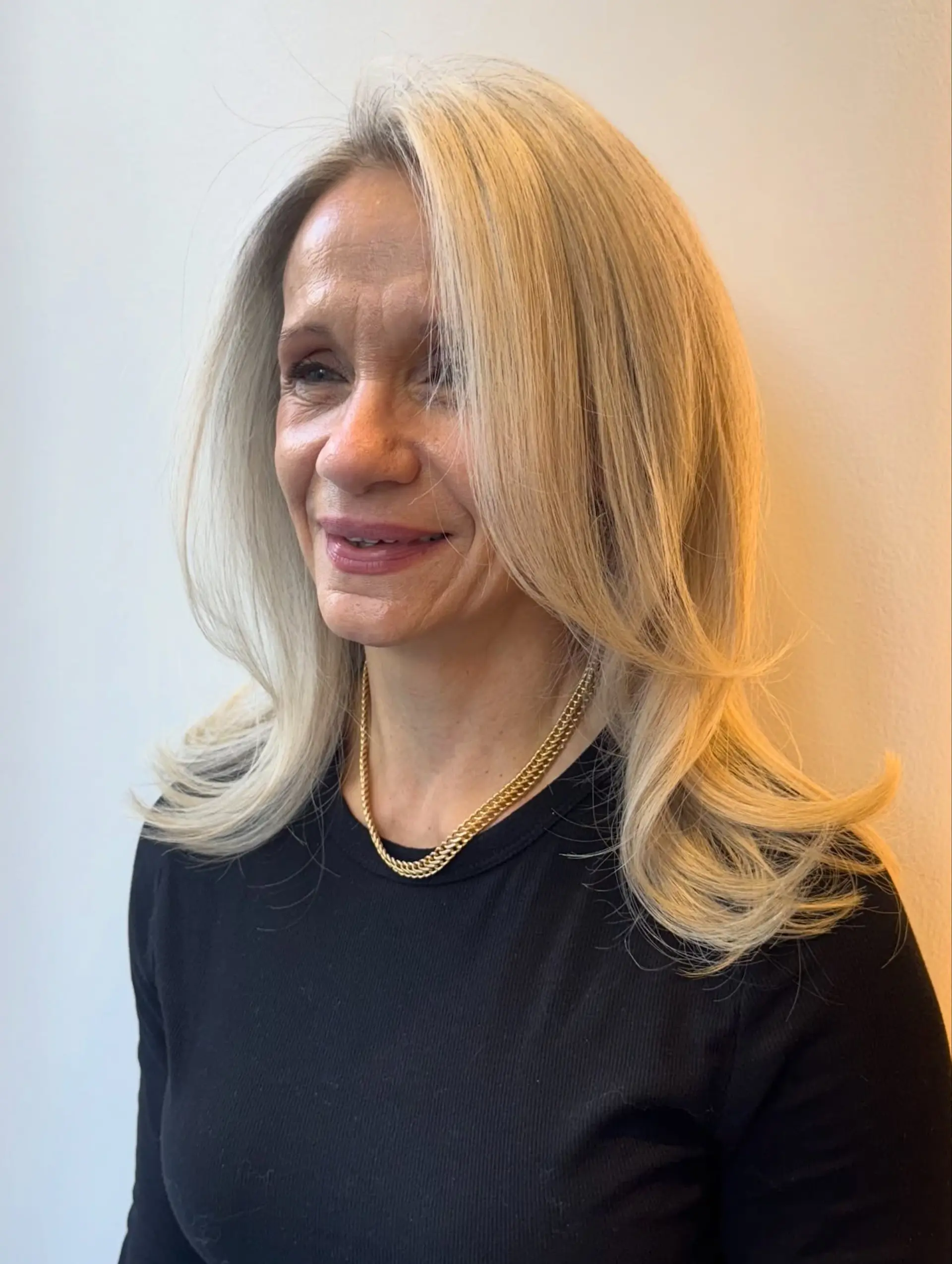 Medium-length layered haircut styled into a soft blowout with flipped, outward-curling ends and long face-framing layers. 1