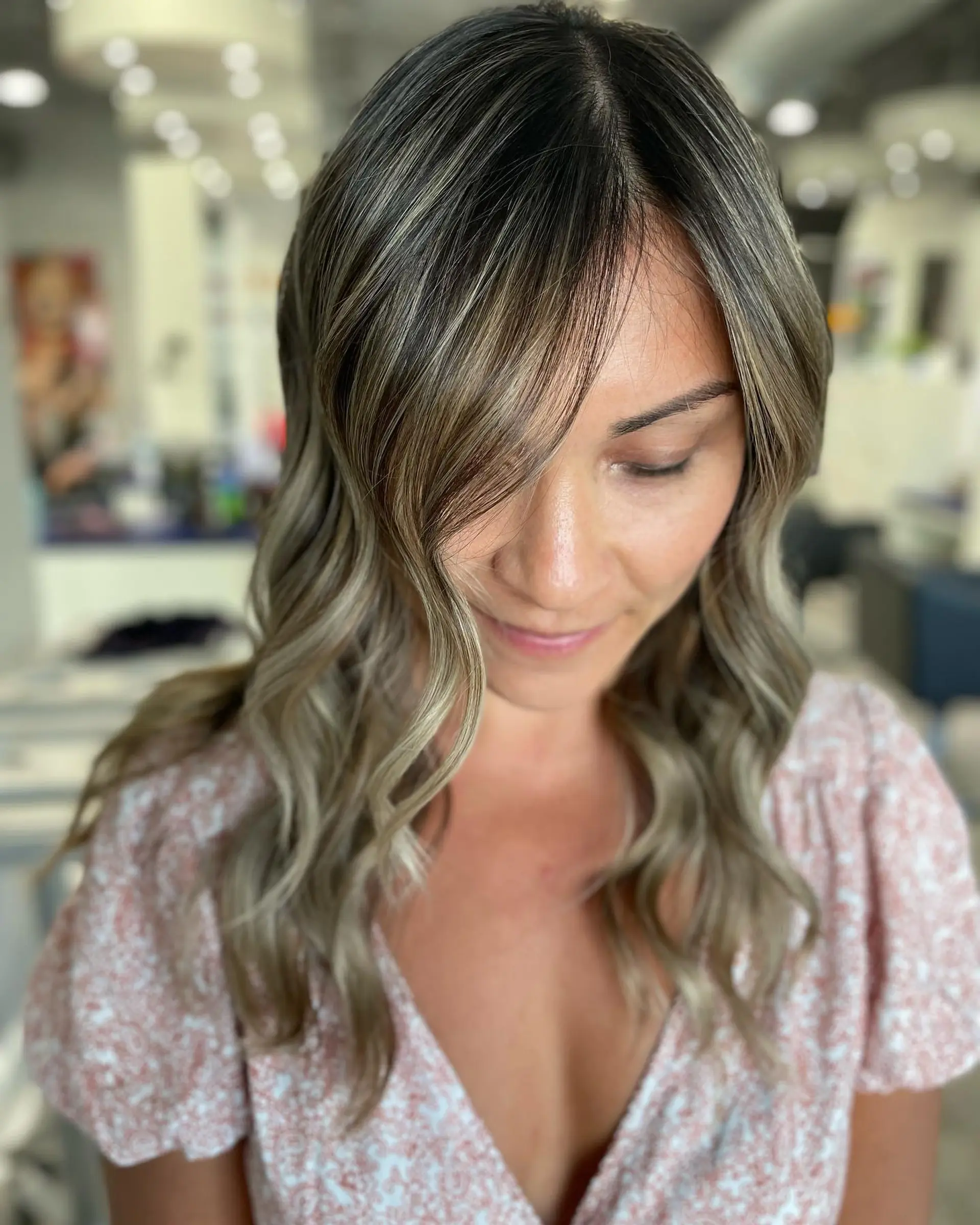 A long, wavy hairstyle with ash blonde balayage and soft curtain bangs. 2