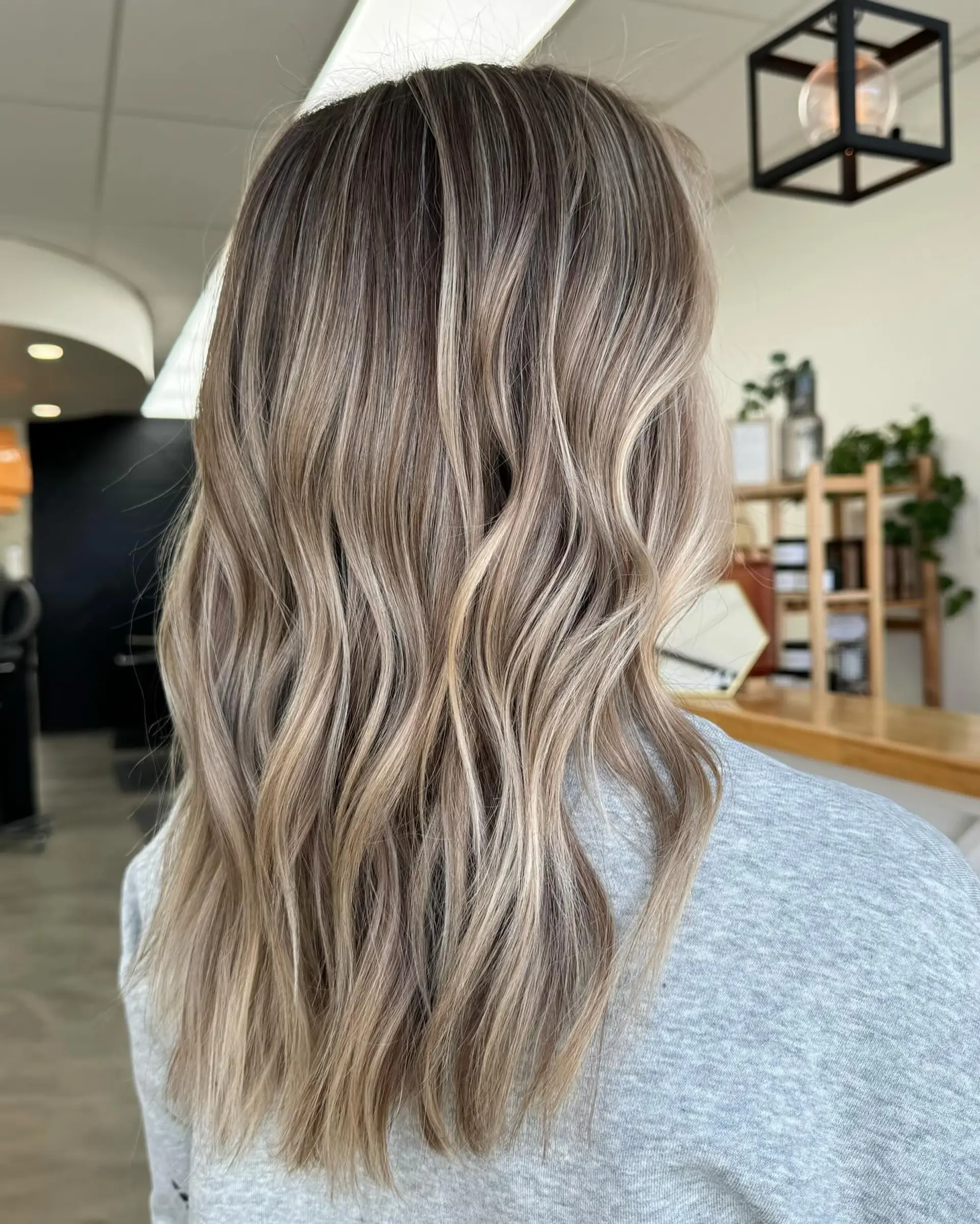 Long hair featuring a seamless dimensional blend of cool and neutral blonde highlights styled in loose, lived-in waves. 1