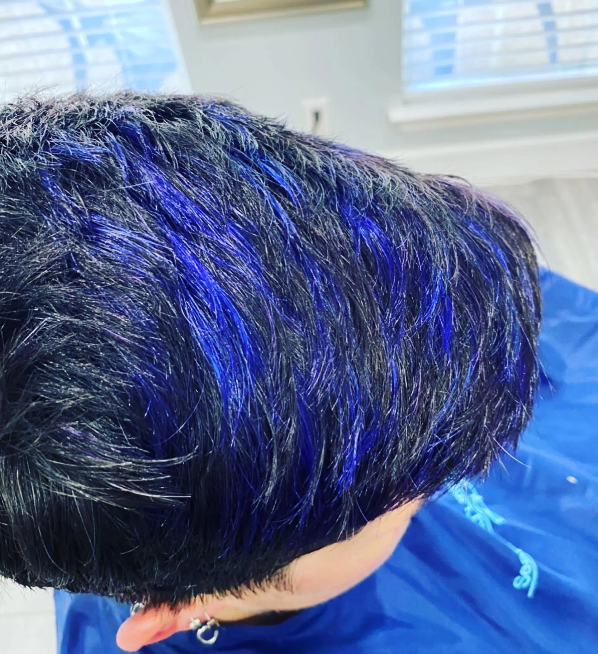 A textured short crop featuring striking vibrant purple and blue highlights over dark hair. 1