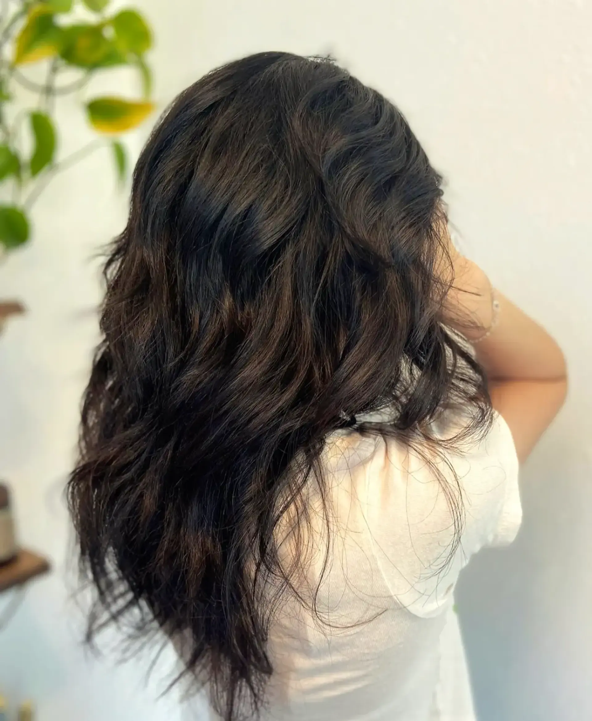 A long dark brunette shag haircut featuring textured layers and effortless wavy movement. 1