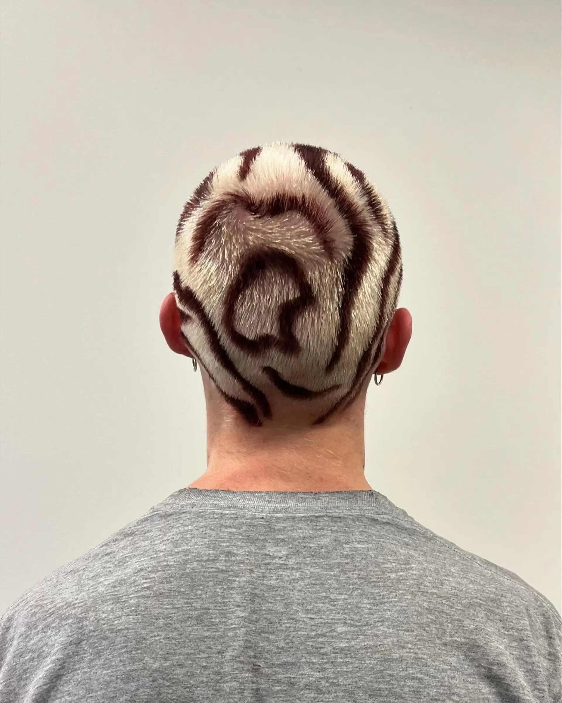 A close buzz cut featuring a high-contrast blonde base painted with intricate, dark brown contour swirls. 1