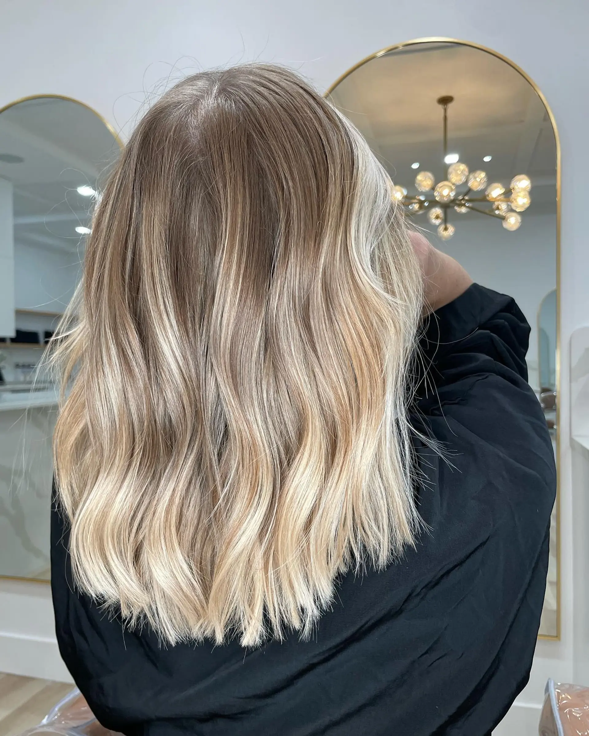 Medium-length dimensional blonde hair styled with soft, textured waves and a natural root blend. 1