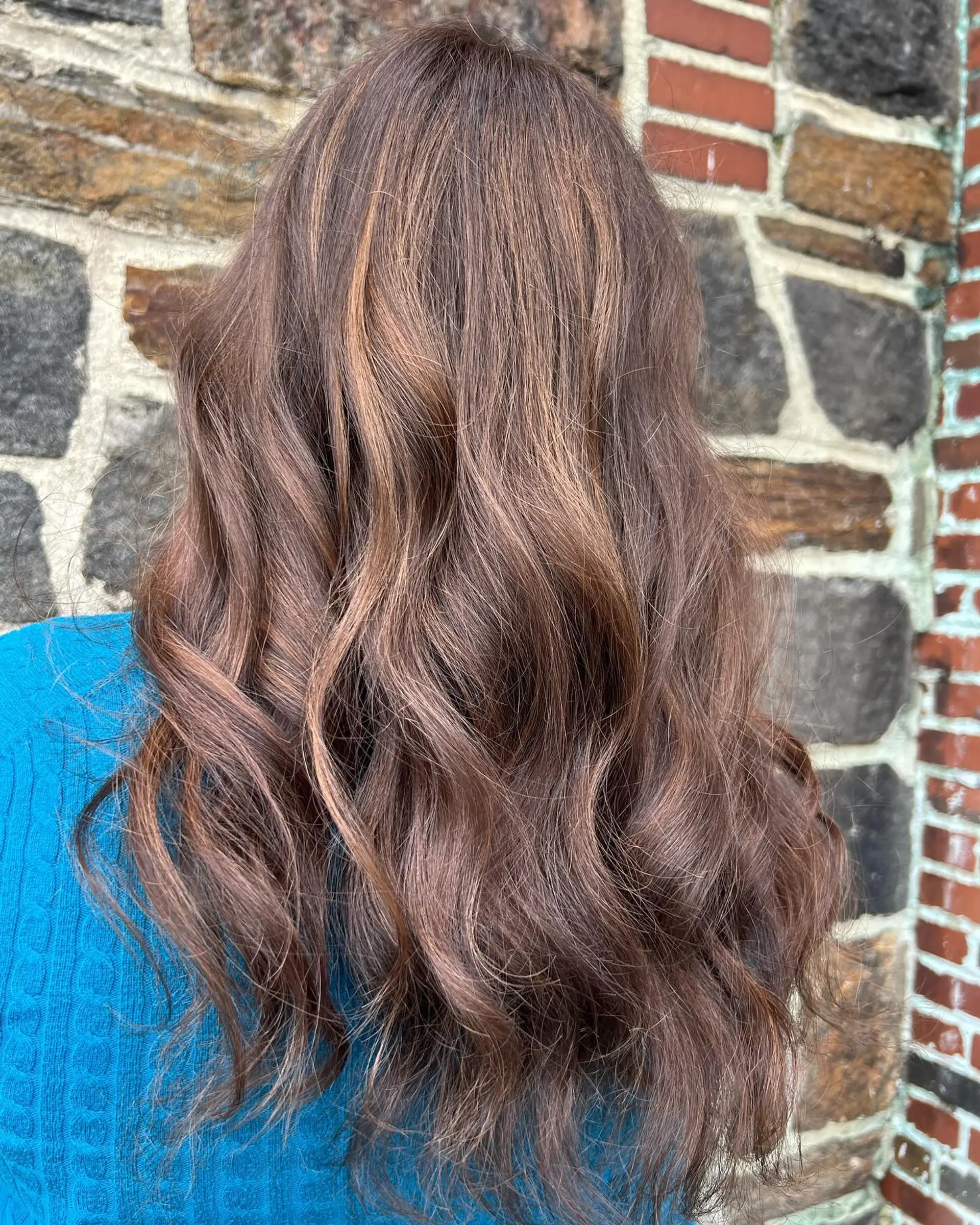 Long, tousled brunette hair styled with soft waves and subtle caramel highlights. 1