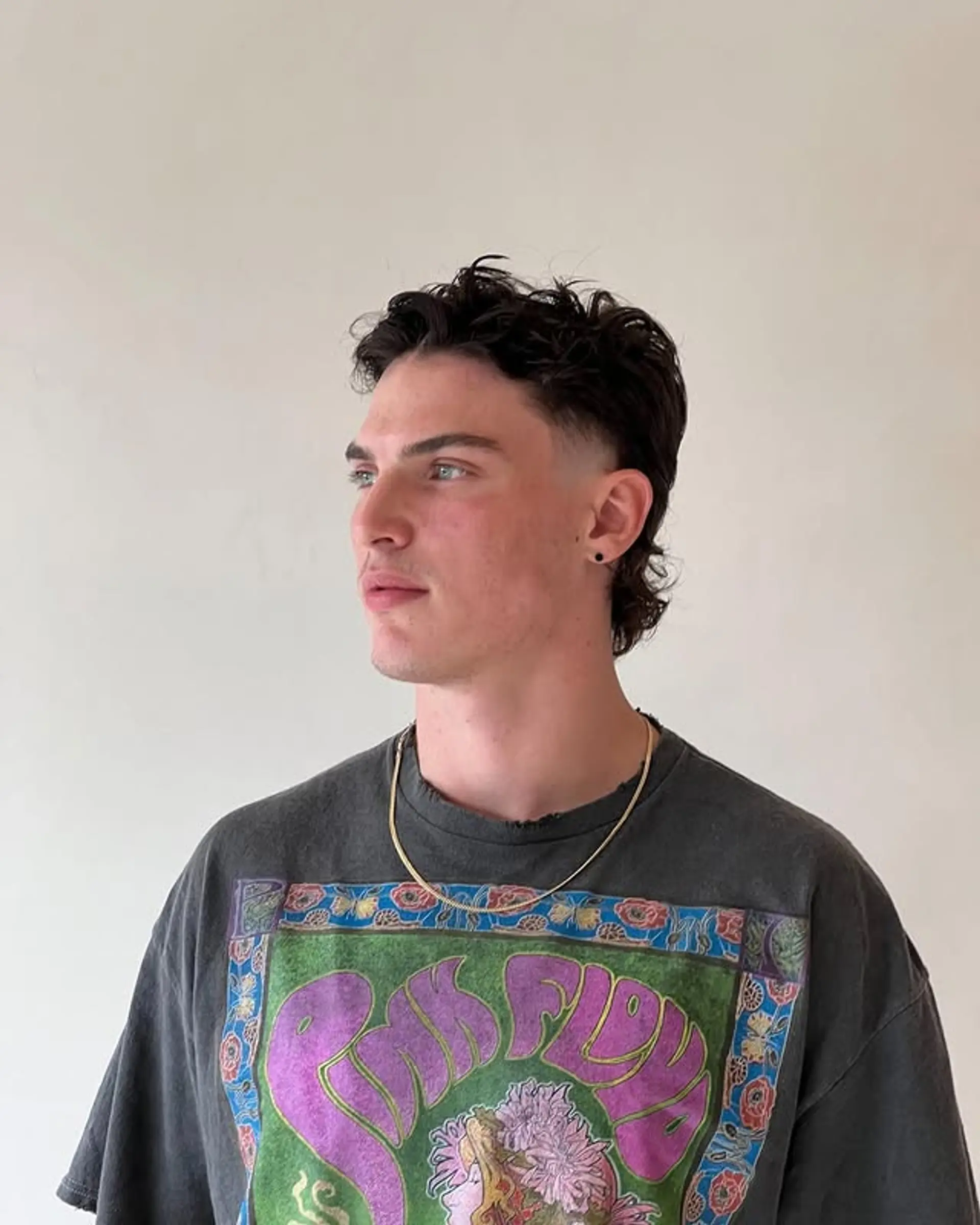 A modern mullet with a taper fade, featuring textured, wavy hair. 1