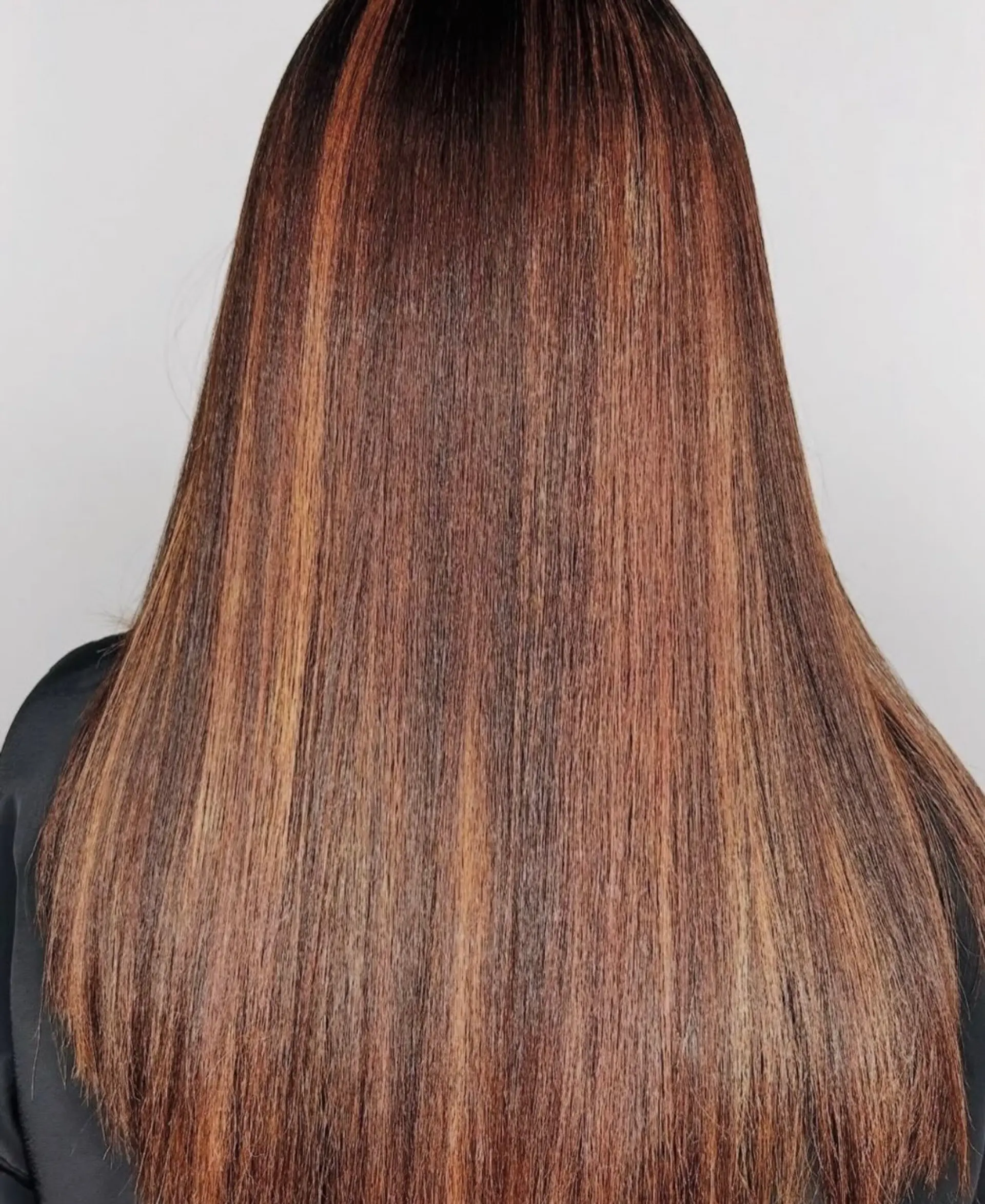 Long straight hair featuring warm copper and caramel balayage highlights. 1